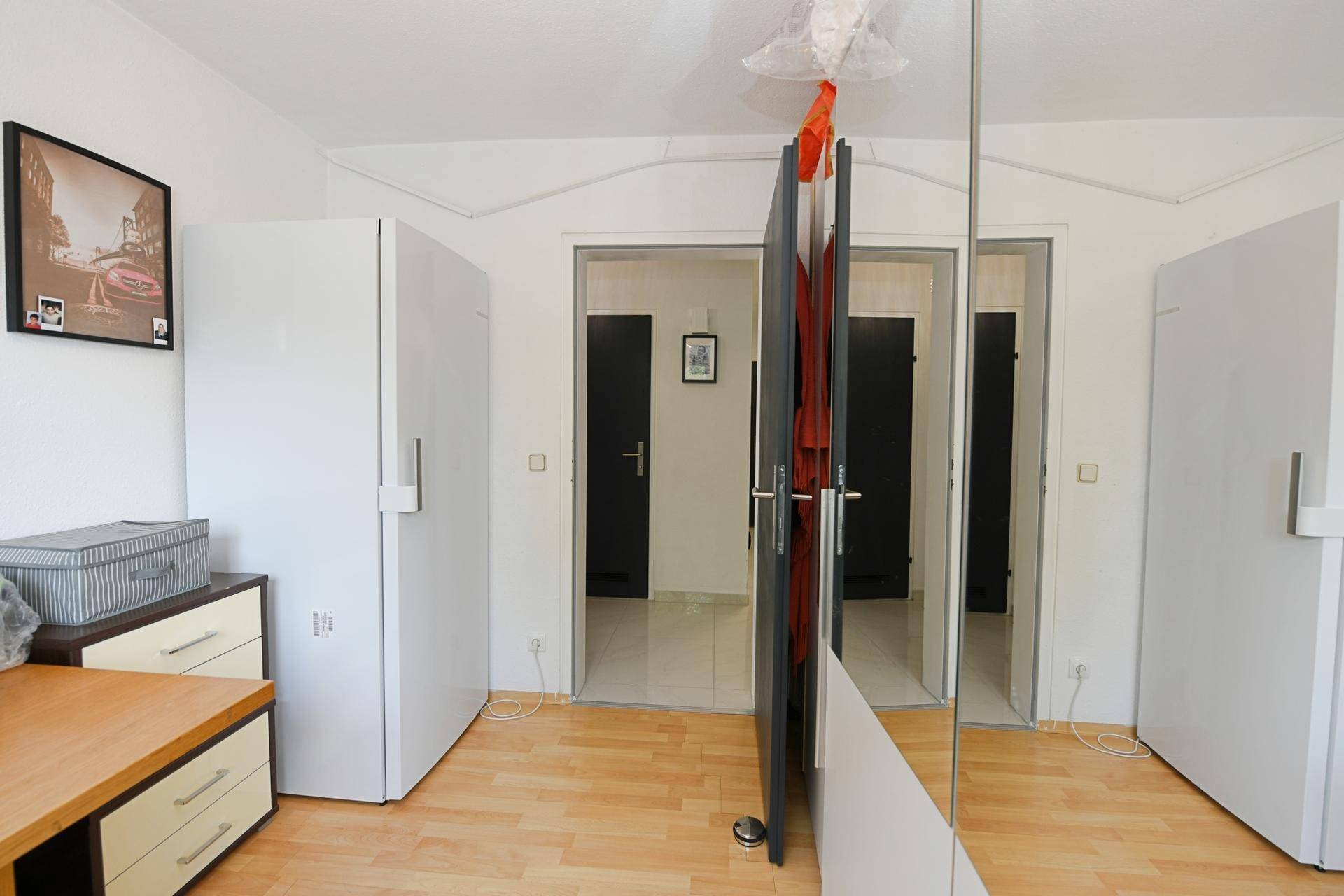 Praktisches Zimmer mit Schreibtisch und großem Spiegelschrank, der den Flur reflektiert.