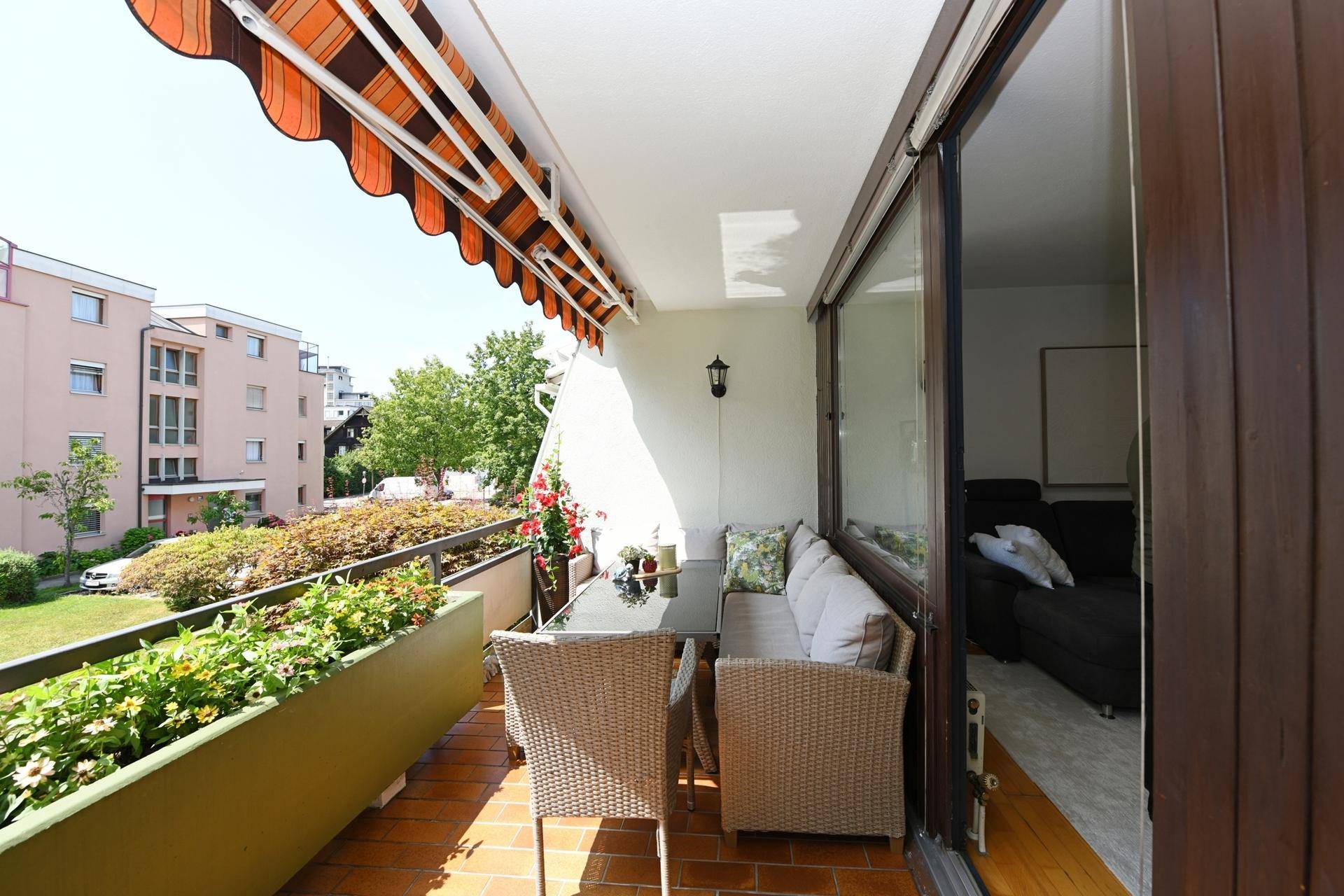 Geräumiger Balkon mit Sitzgelegenheiten, Markise und Ausblick auf die Umgebung.