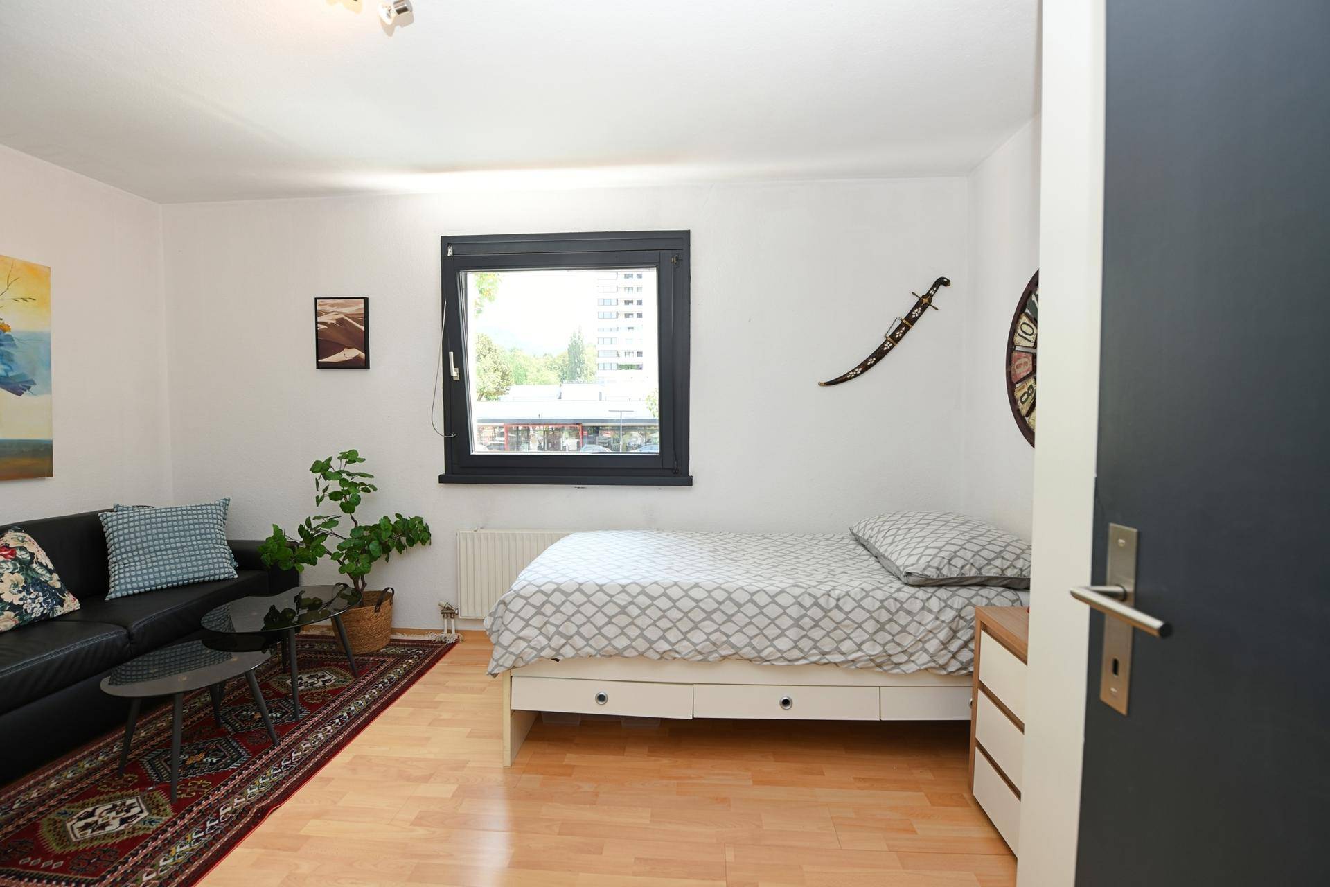 Freundliches Kinderzimmer mit Einzelbett, kleinem Sofa und Holzboden.