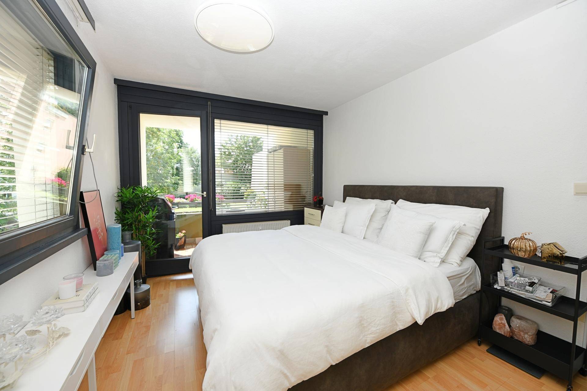 Helles Schlafzimmer mit Doppelbett, Holzboden und direktem Zugang zum Balkon.