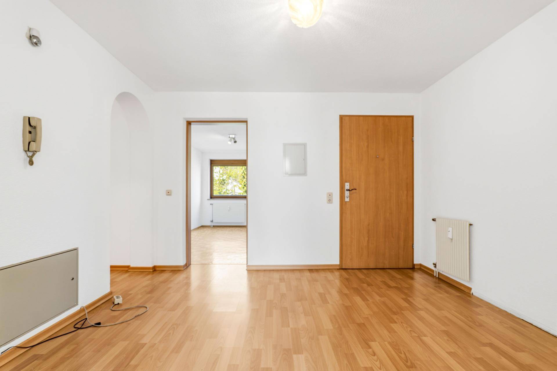 Heller Flur mit Holzboden, weiß gestrichenen Wänden und Zugang zu weiteren Räumen.