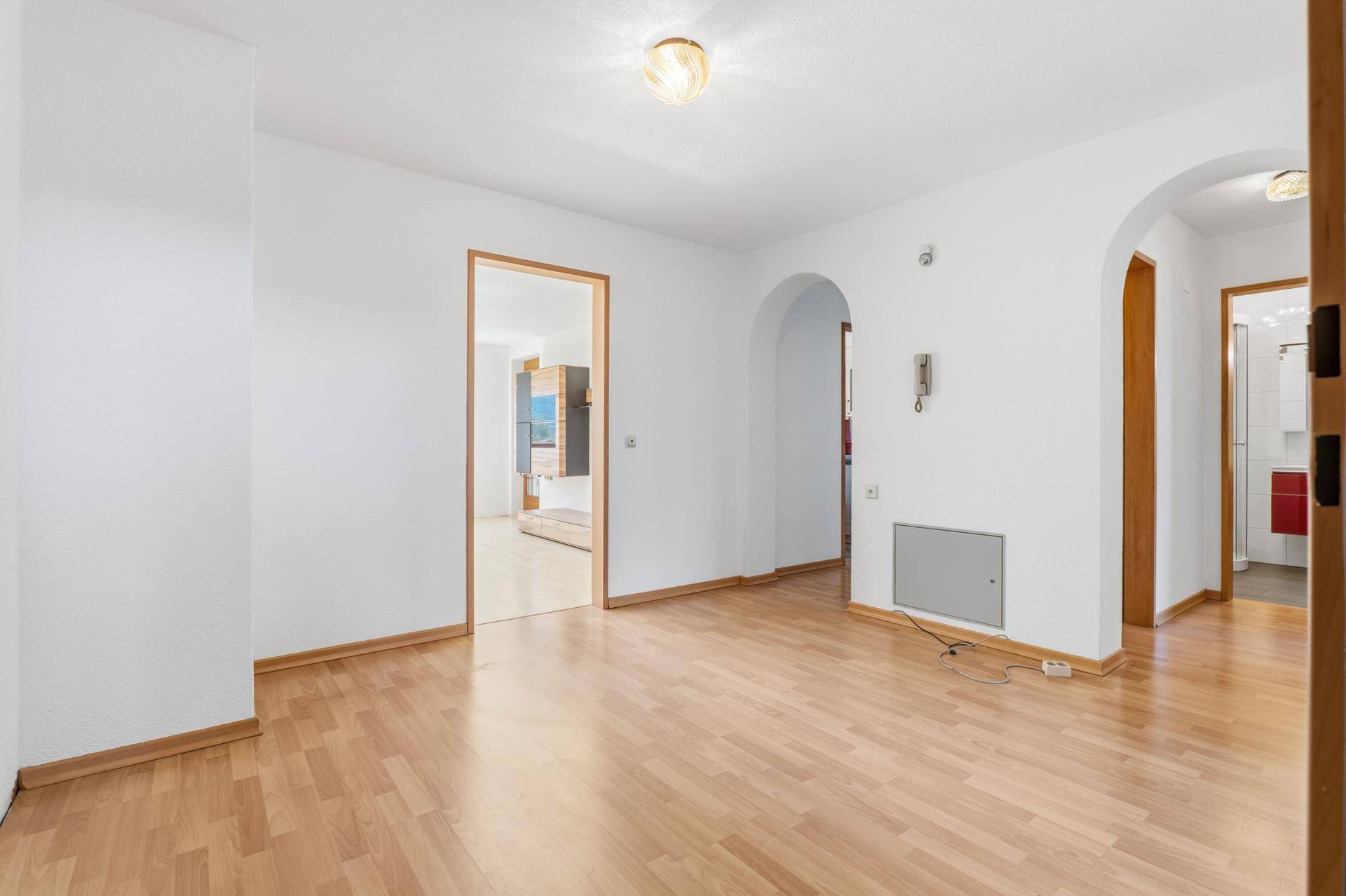 Geräumiger Flur mit Holzboden, weißen Wänden und Rundbögen zu angrenzenden Zimmern.