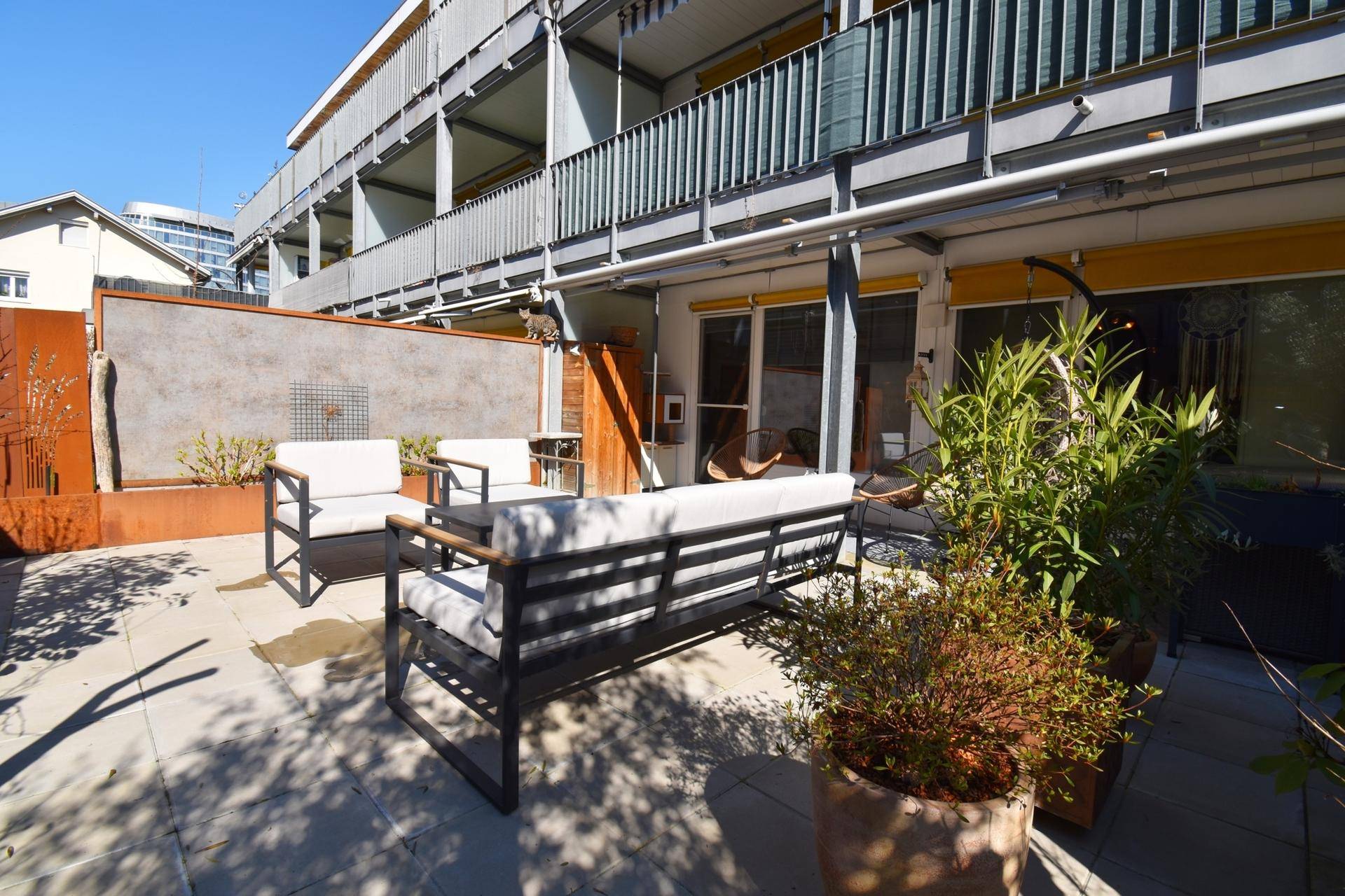 Geräumige Terrasse mit modernen Gartenmöbeln und Blick auf das Gebäude.