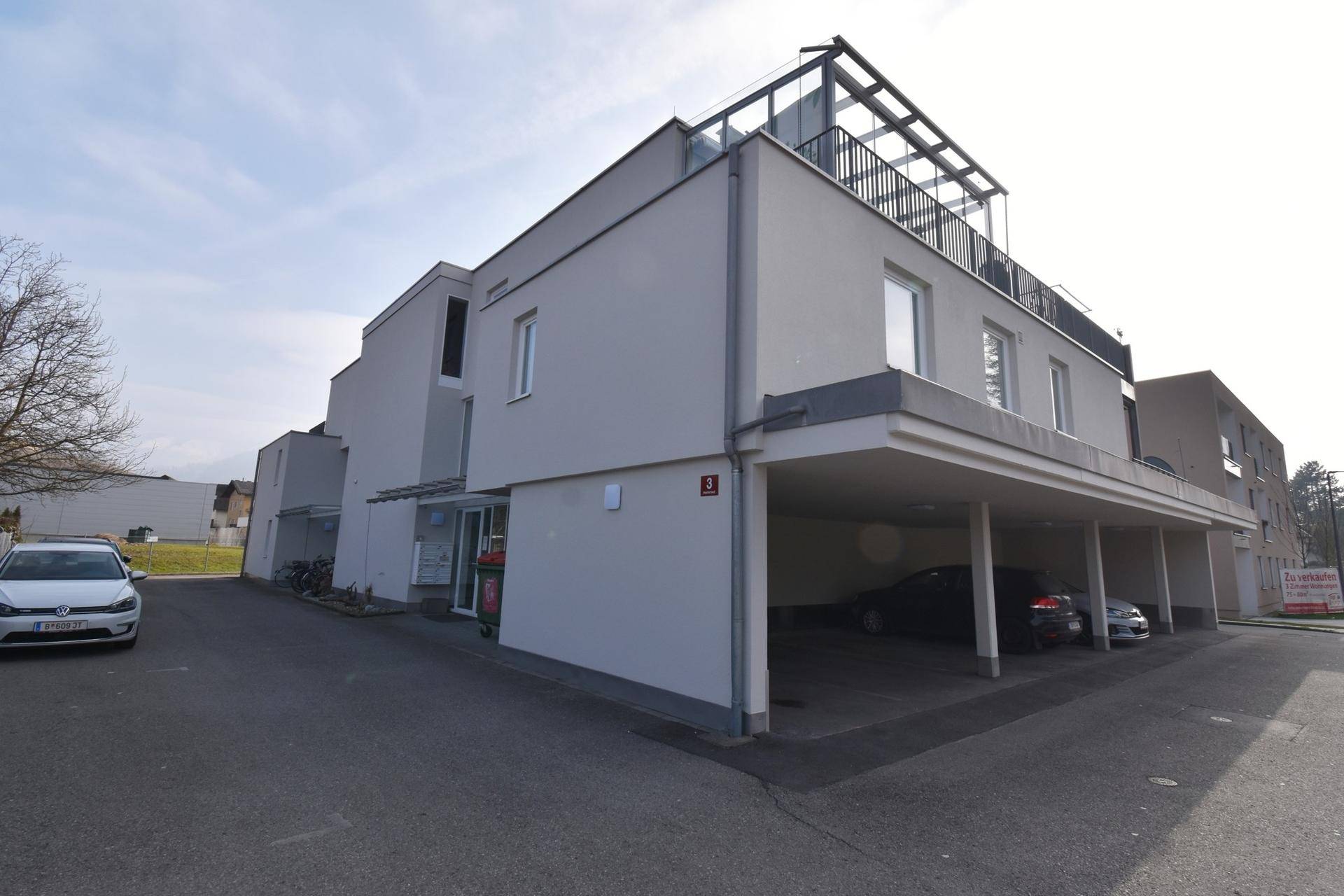 Ansicht eines modernen Wohngebäudes mit klaren Linien und Carport-Bereich.