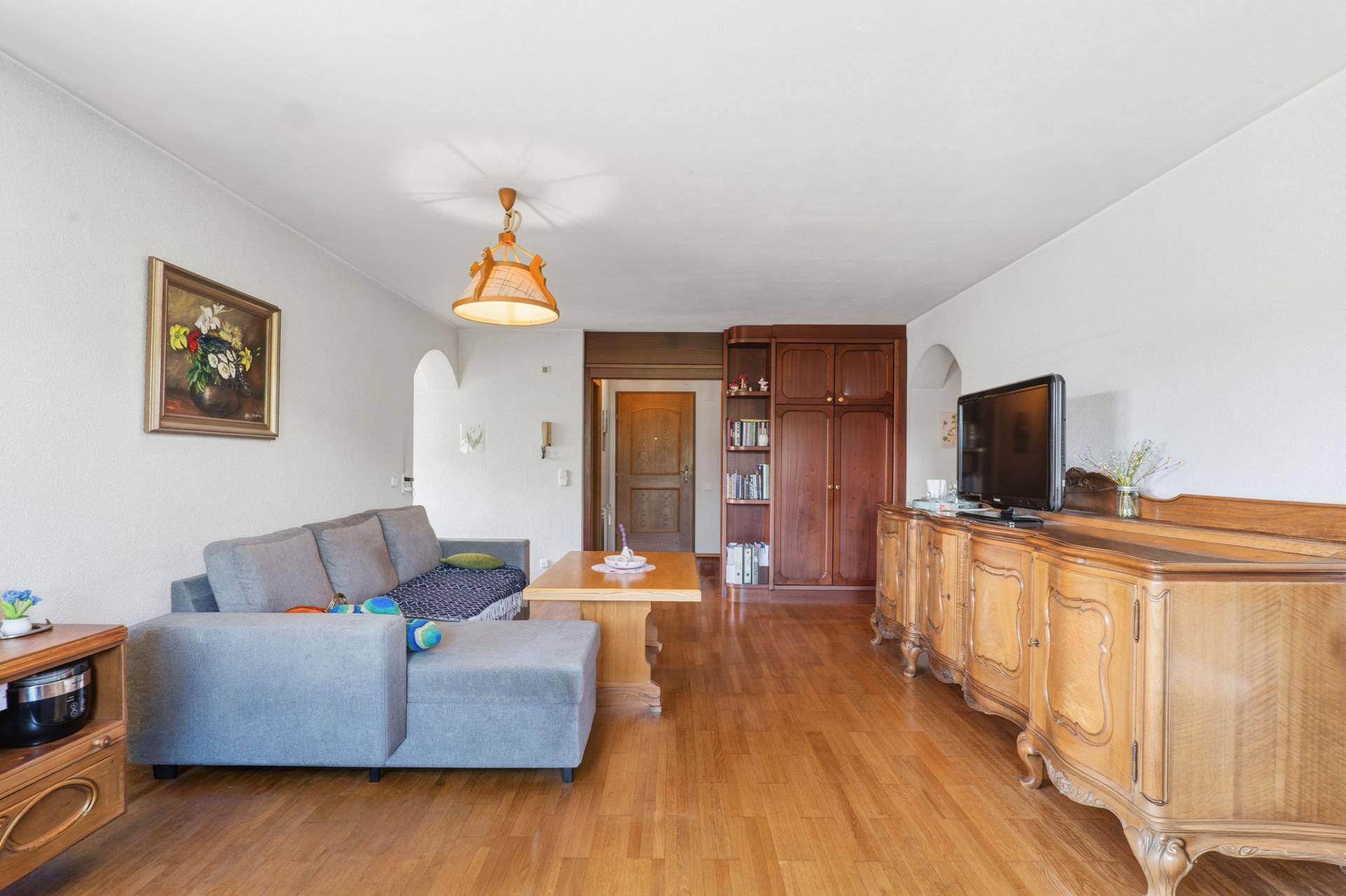 Geräumiges Wohnzimmer mit Holzboden, traditionellen Holzmöbeln und Einbauschränken.