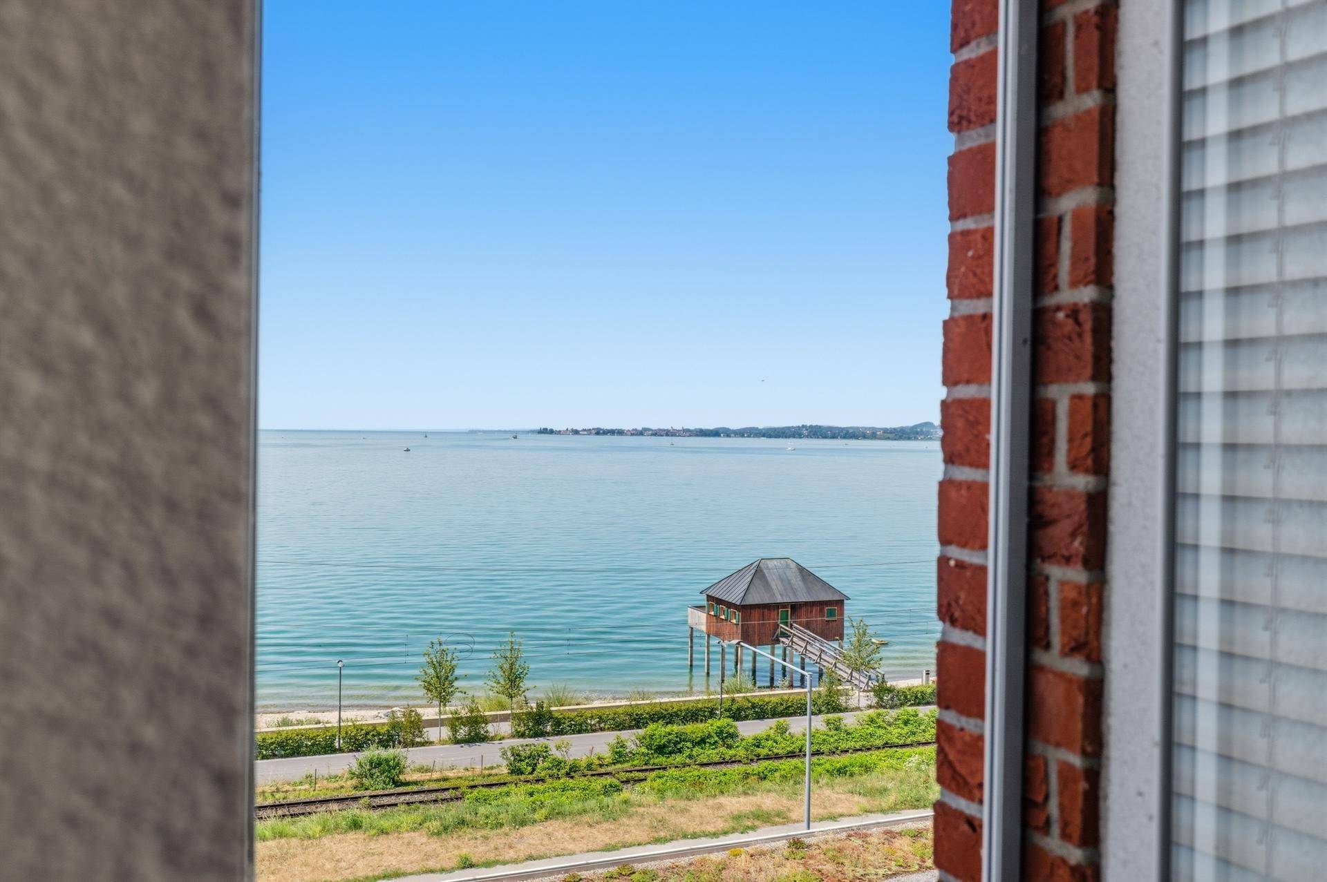 Atemberaubender Seeblick aus dem Fenster mit einem kleinen Haus am Ufer.