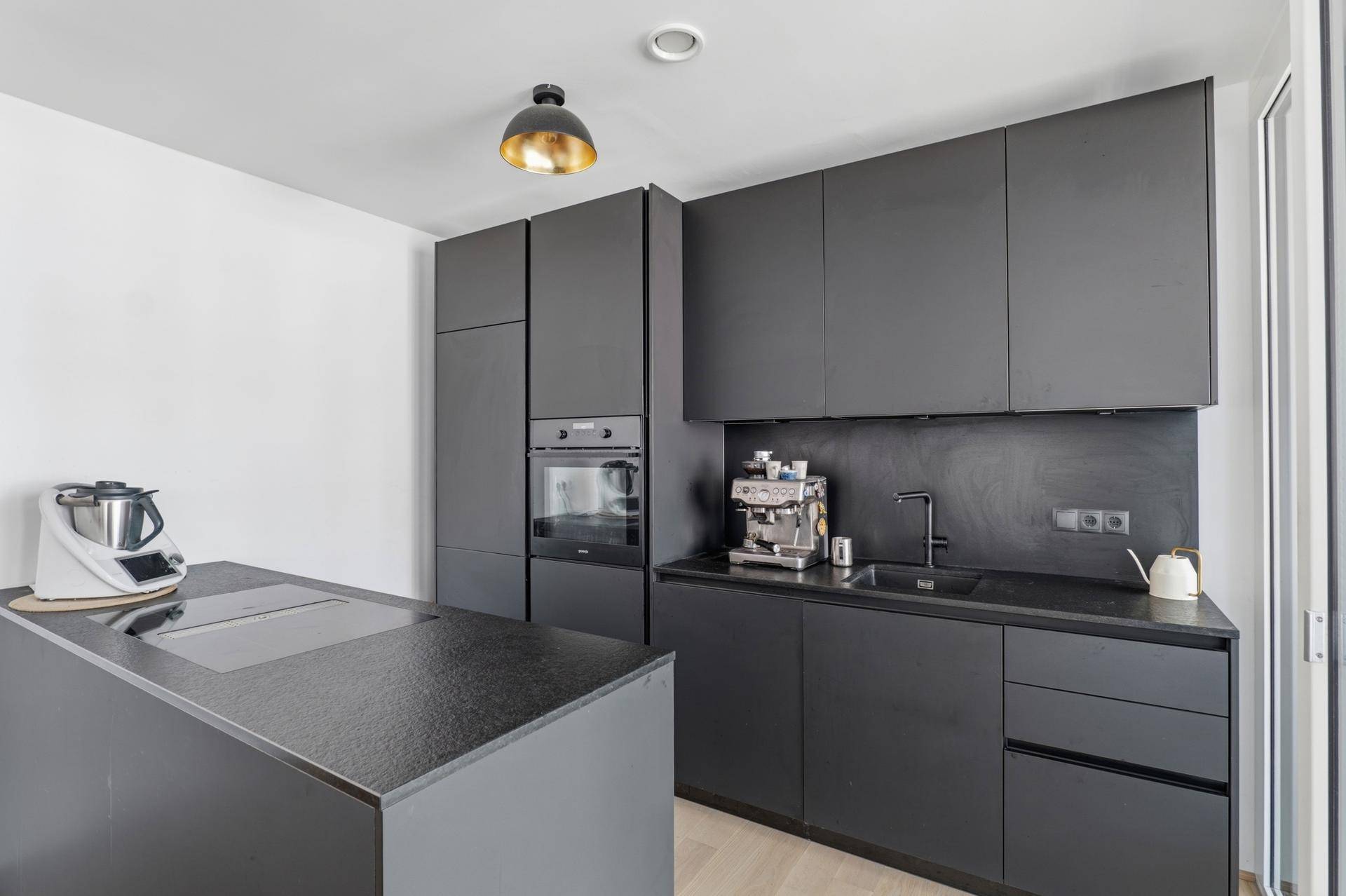 Elegante schwarze Einbauküche mit modernen Geräten und minimalistischem Design.