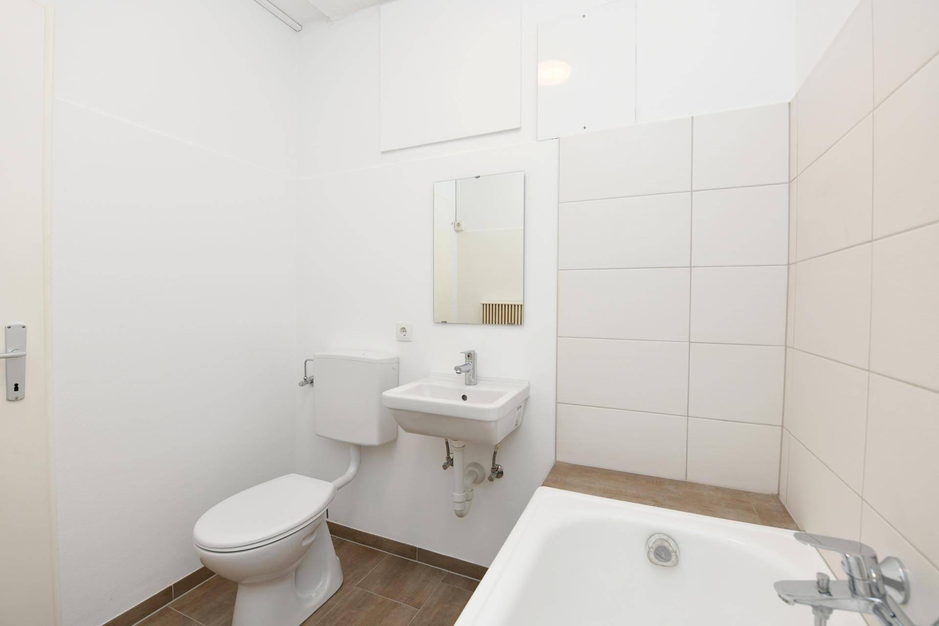 Funktionales Badezimmer mit Badewanne, WC und Waschbecken in schlichtem Design.