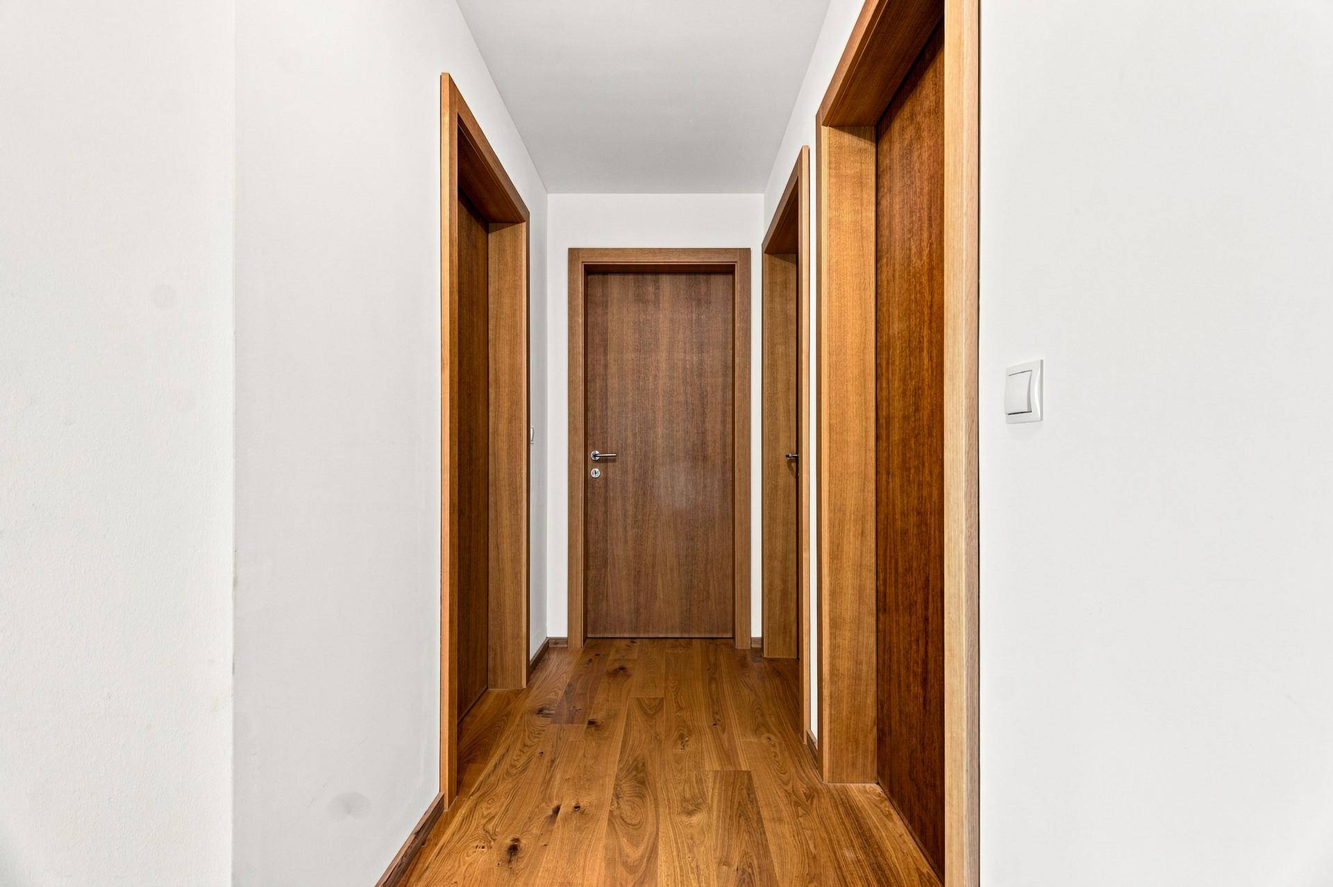 Heller Flur mit Holzboden und mehreren Holztüren, die zu den verschiedenen Räumen führen.