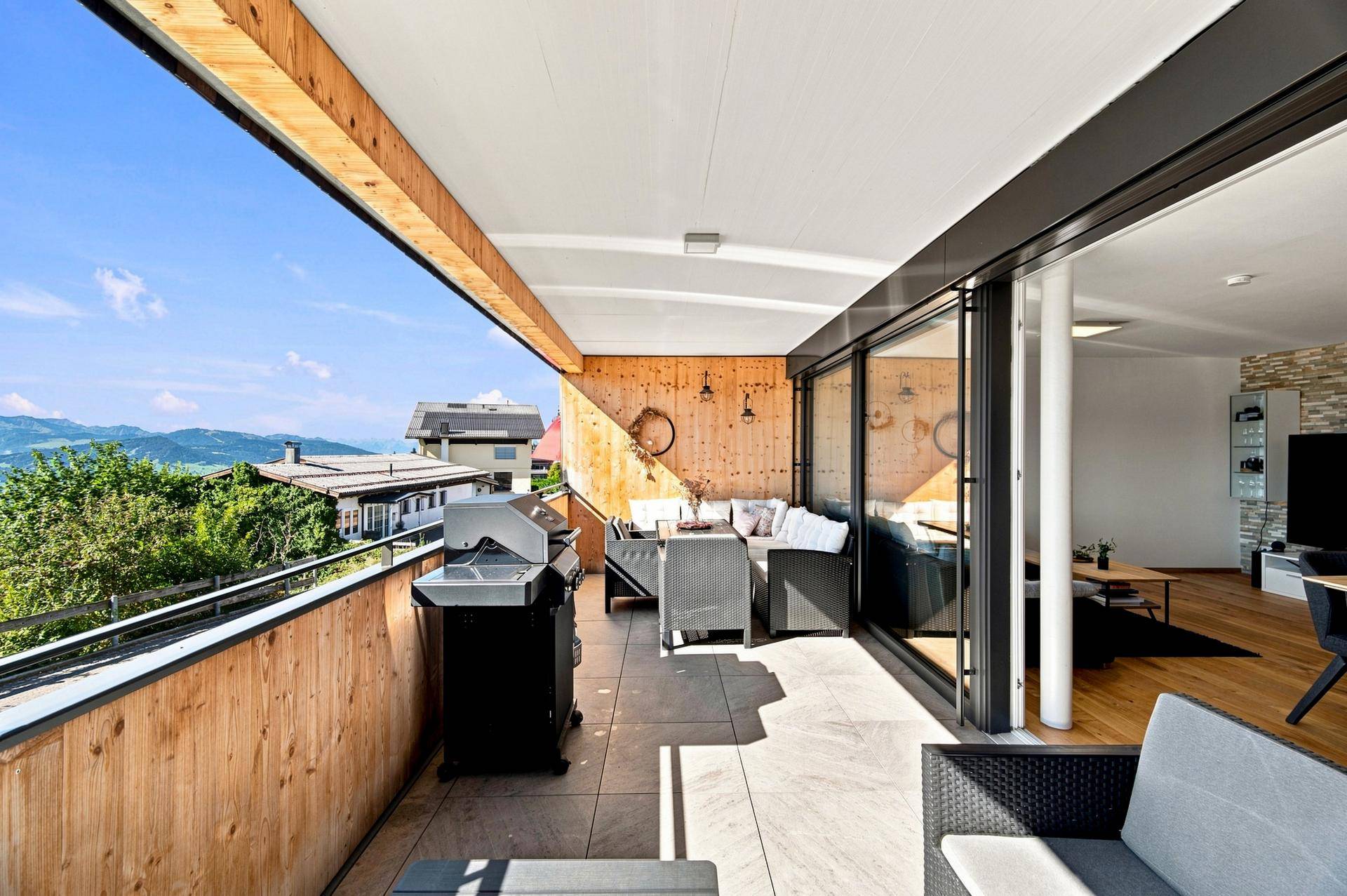 Breite Terrasse mit Essbereich, Grill und Lounge-Möbeln, die einen herrlichen Bergblick bietet.