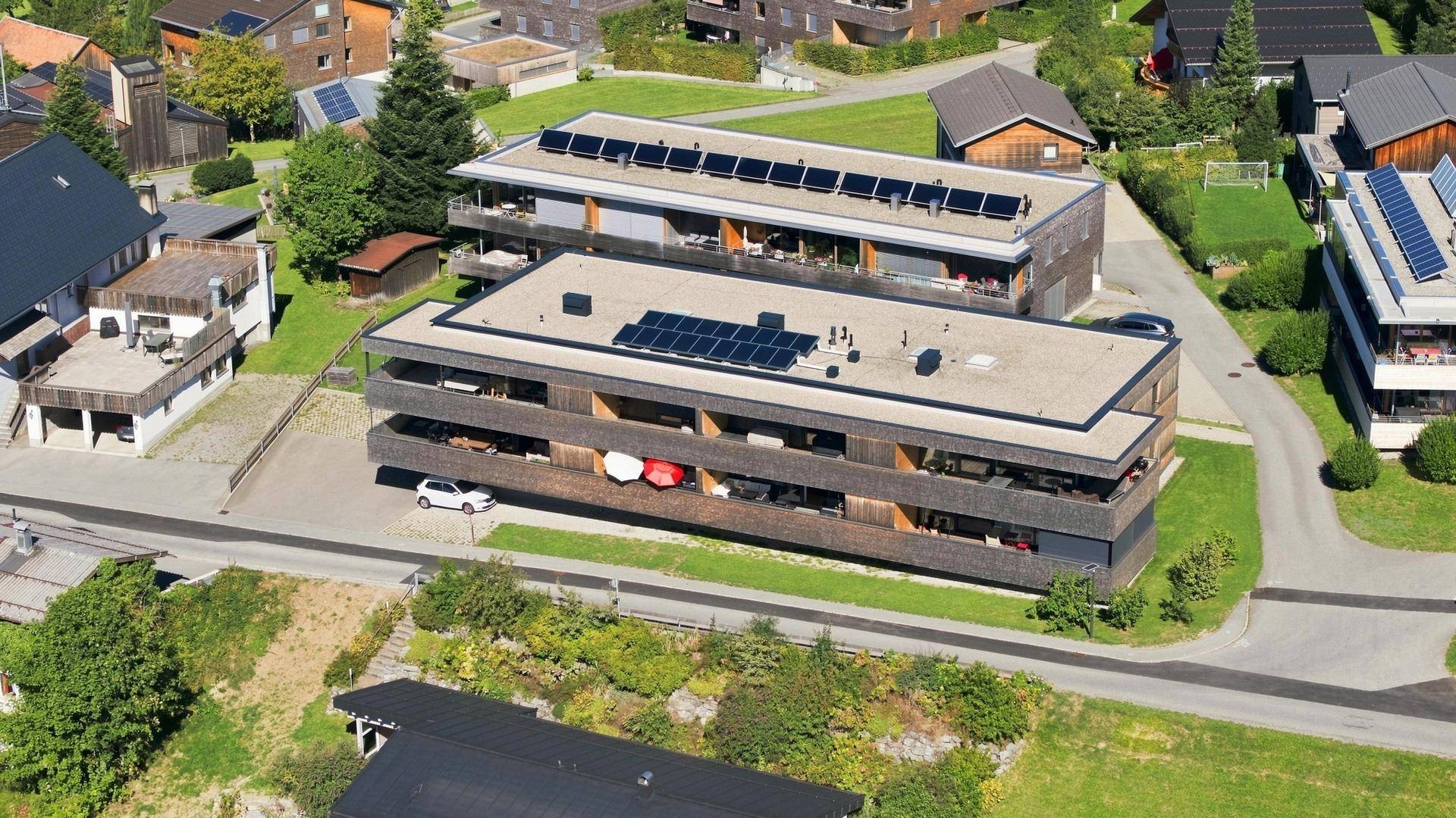 Luftaufnahme eines modernen Apartmentkomplexes mit Flachdächern und Solaranlagen in ländlicher Umgebung.