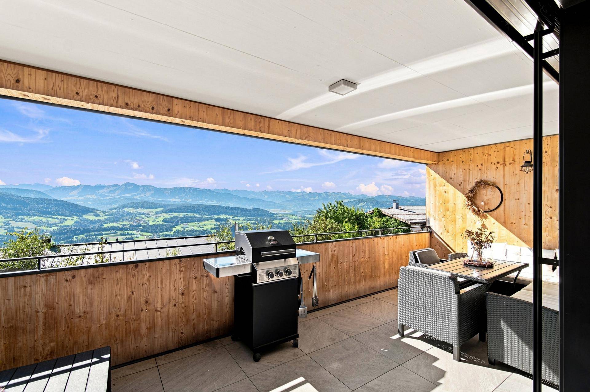 Geräumige Terrasse mit Essbereich, Grill und weitem Blick auf die malerische Bergwelt.