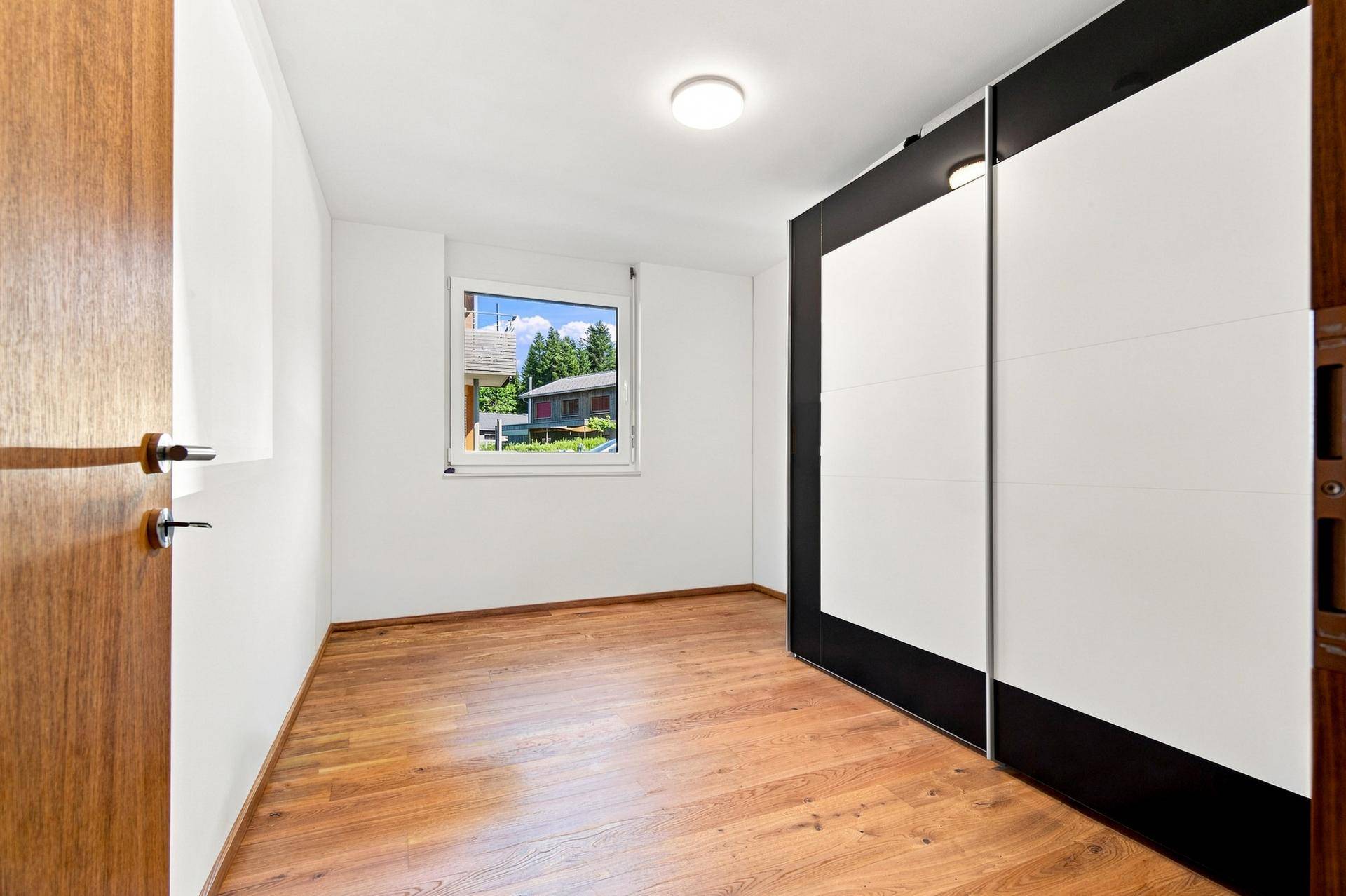 Helles Schlafzimmer mit Holzboden und großem Schiebetürenschrank, ideal als Kinder- oder Gästezimmer.