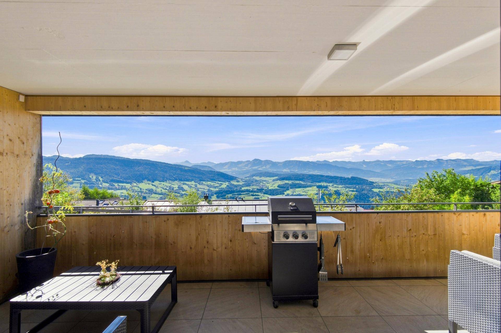 Große Terrasse mit Grillbereich und atemberaubendem Panoramablick auf die umliegende Berglandschaft.