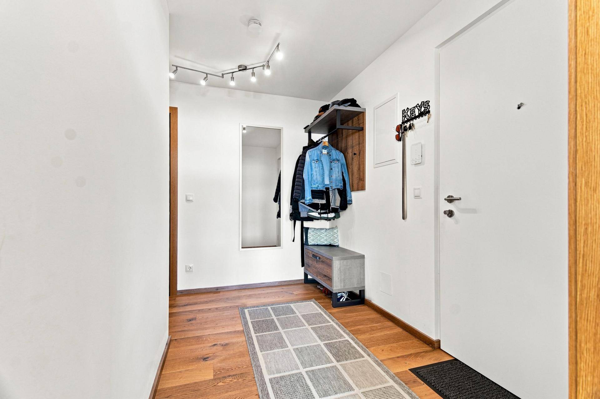 Eingangsbereich mit Holzboden, Garderobe und Spiegel, der einen einladenden Eindruck vermittelt.