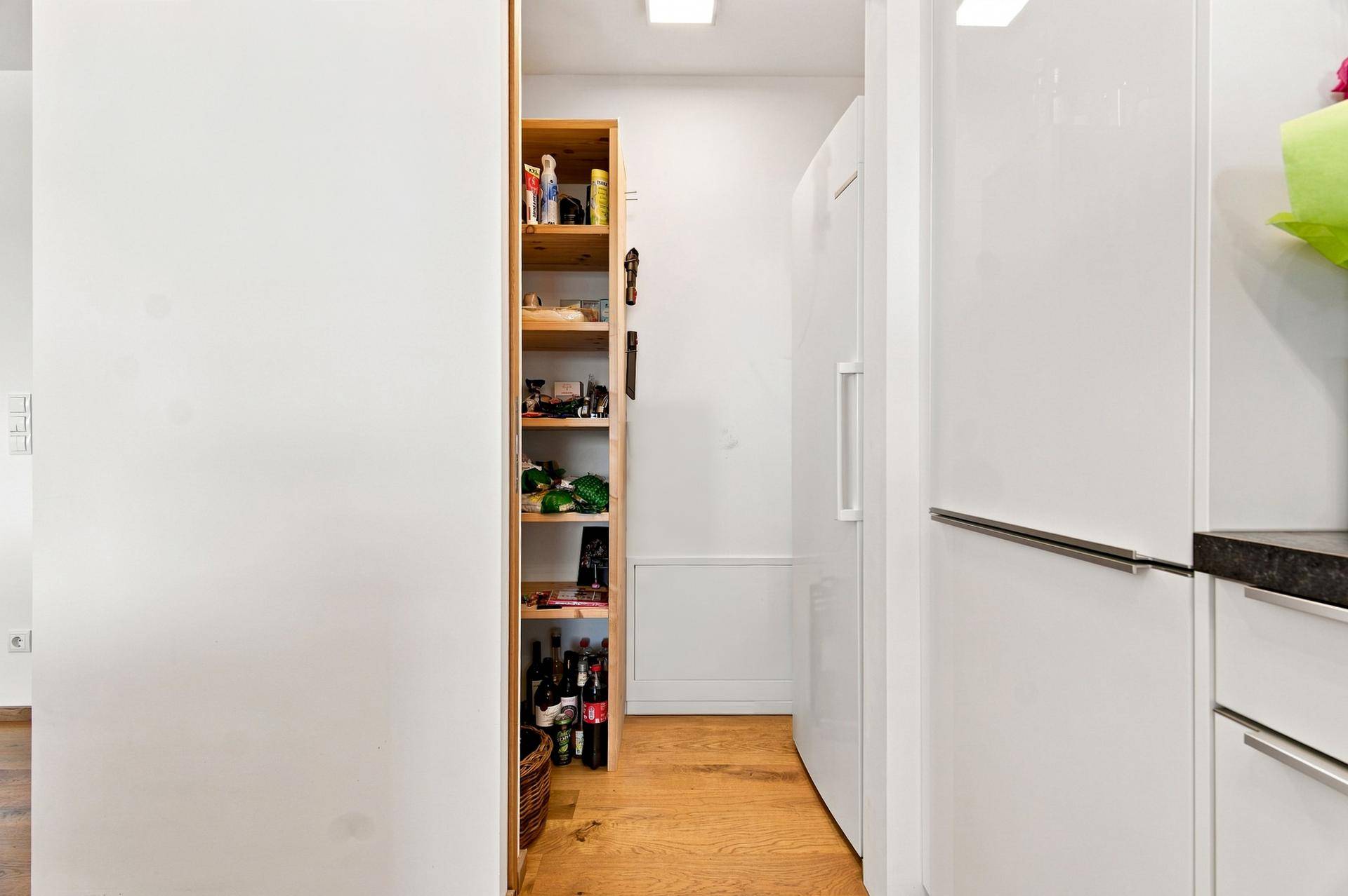 Praktische Speisekammer mit Regalen für Vorräte und integriertem Kühlschrank in der Nähe der Küche.