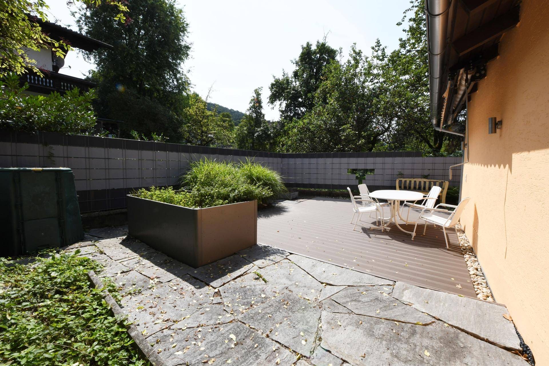 Großzügige Terrasse mit Sitzgelegenheiten und Pflanzenkübeln im Freien.