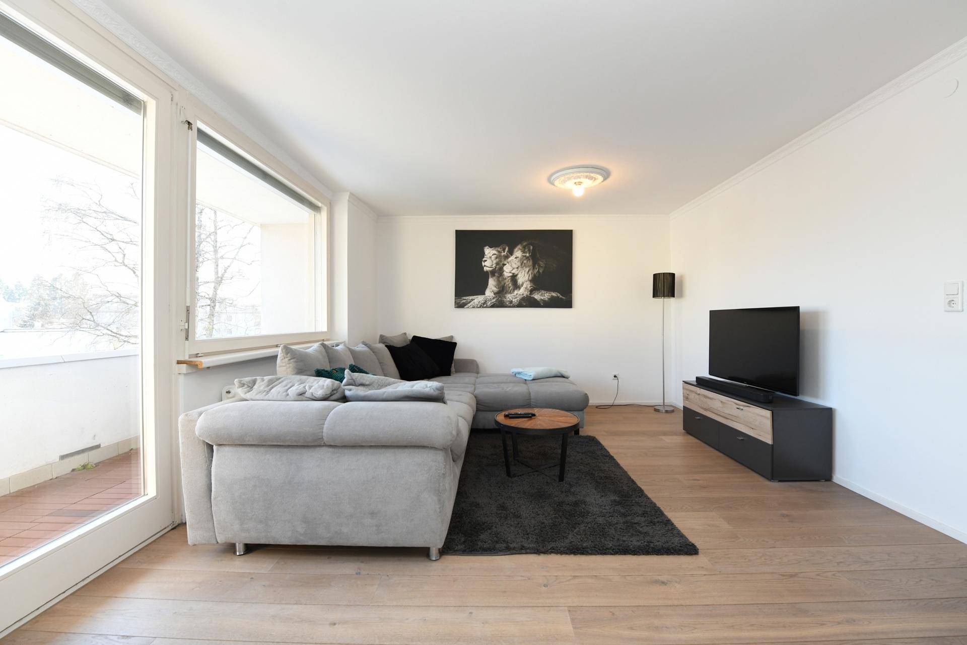 Gemütliches Wohnzimmer mit großem Ecksofa, Fernseher und Holzboden.