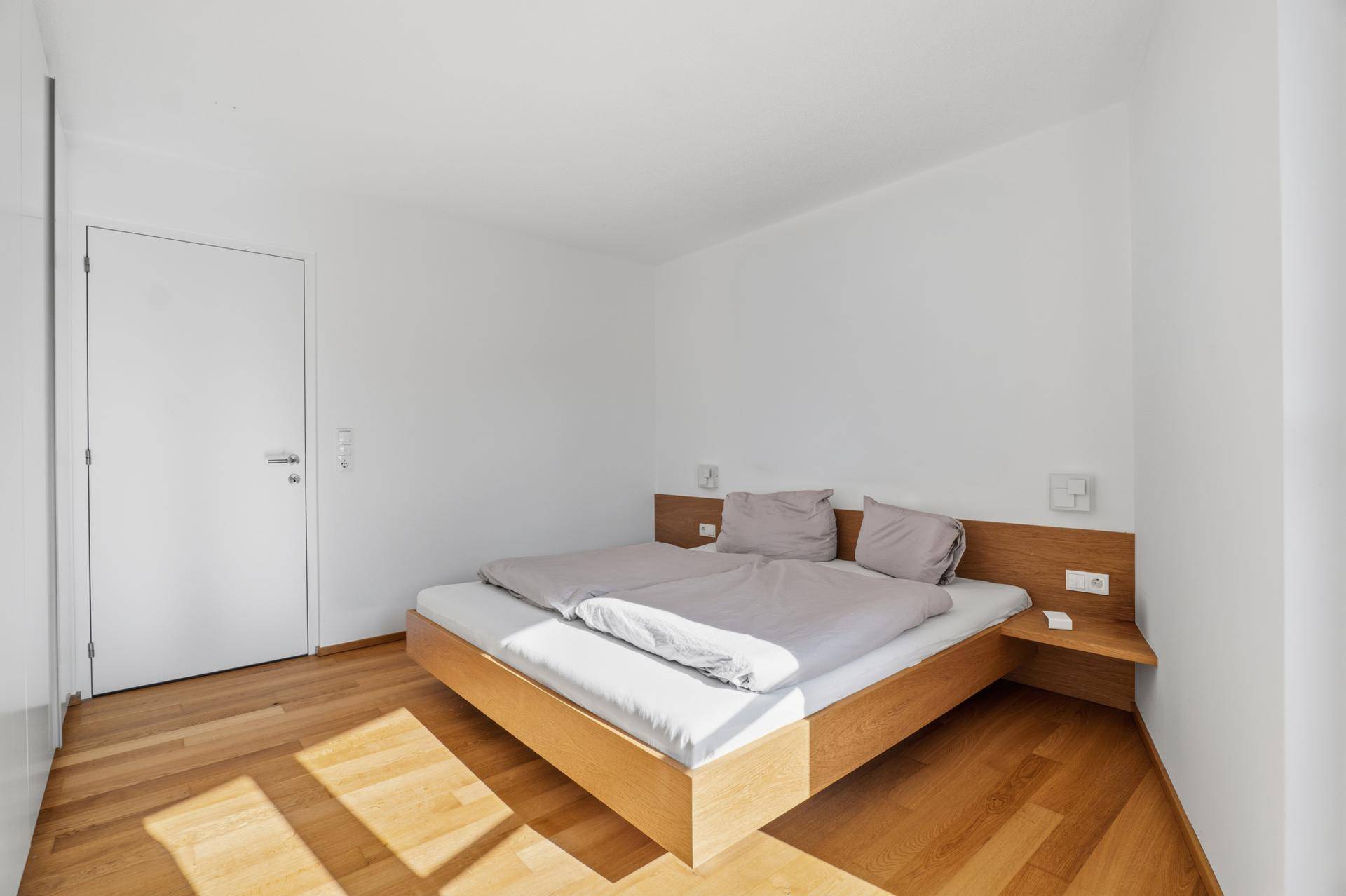 Lichtdurchflutetes Schlafzimmer mit Holzboden und minimalistischem Design.