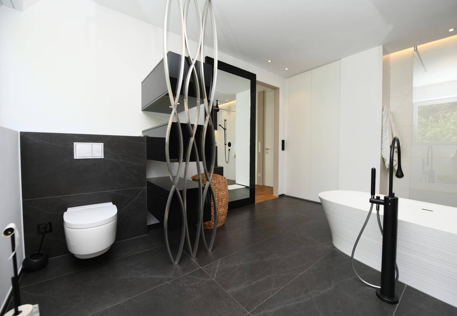 Stilvolles Badezimmer mit wandhängendem WC, dunklen Fliesen und moderner Einrichtung.