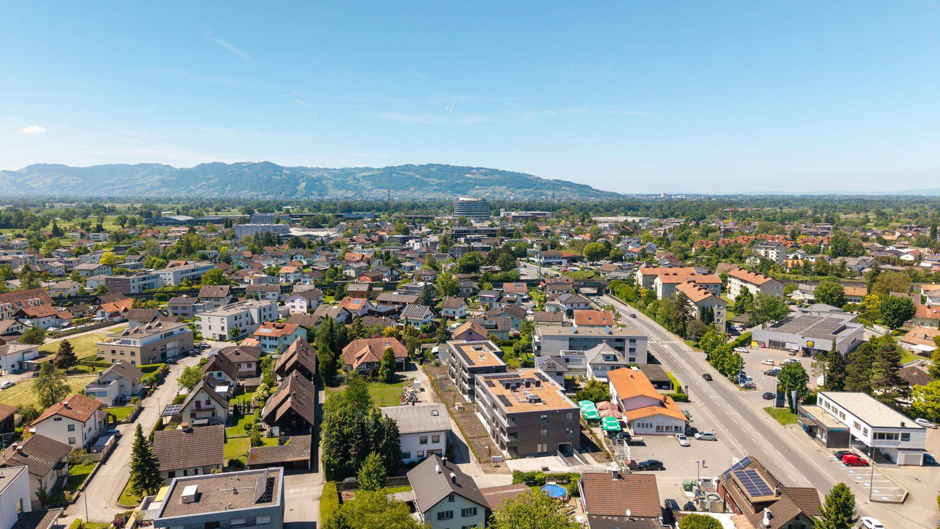 Panoramische Luftaufnahme einer Wohngegend mit weitem Blick über die Landschaft und entfernte Berge am Horizont.