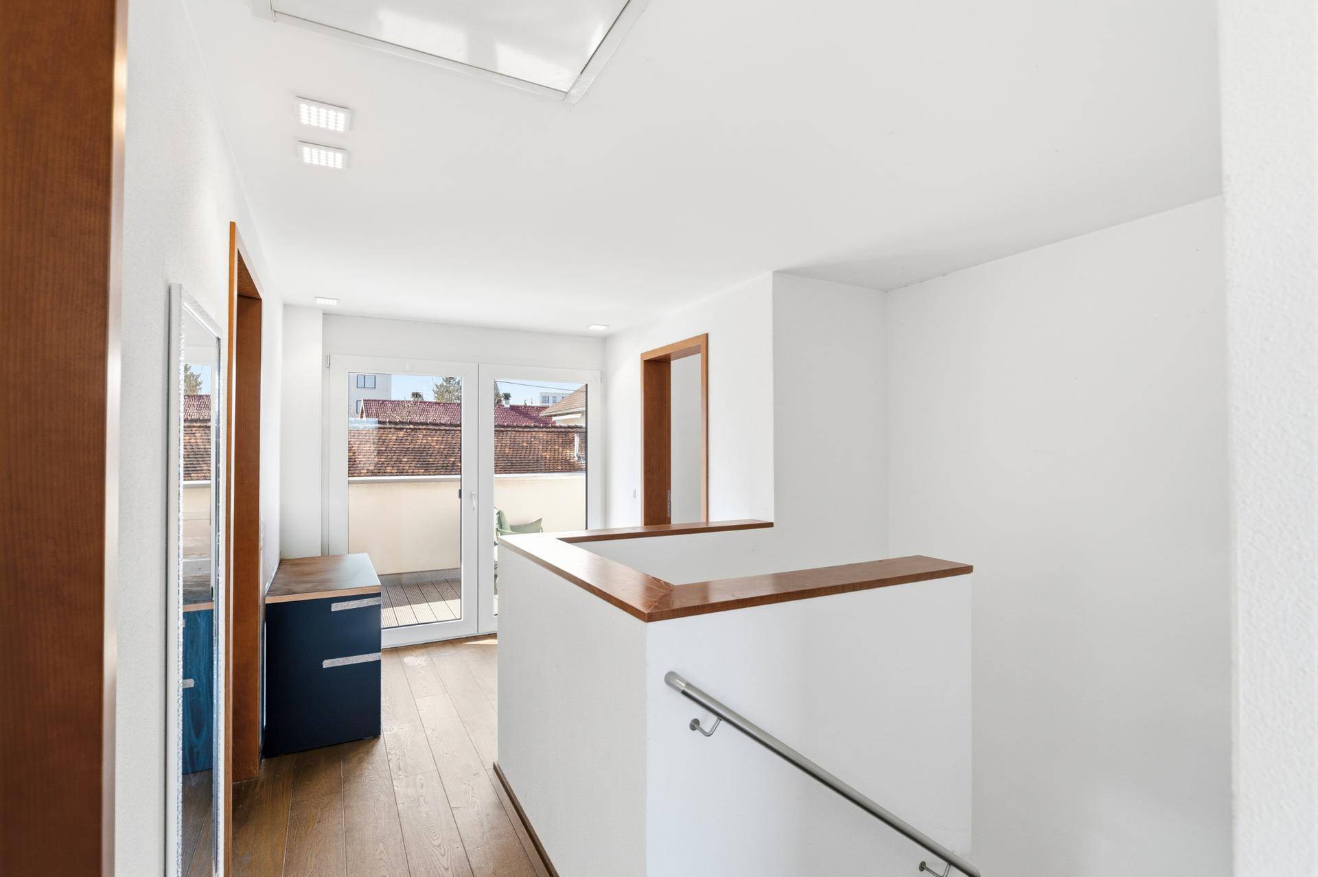 Oberer Flur mit Holzboden, Zugang zum Balkon und viel natürlichem Licht.
