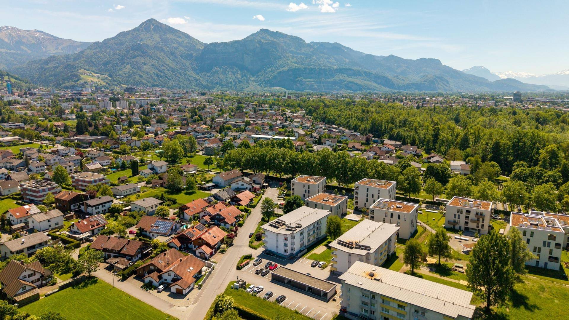 Luftaufnahme einer Stadt mit Wohngebäuden und Bergen am Horizont.