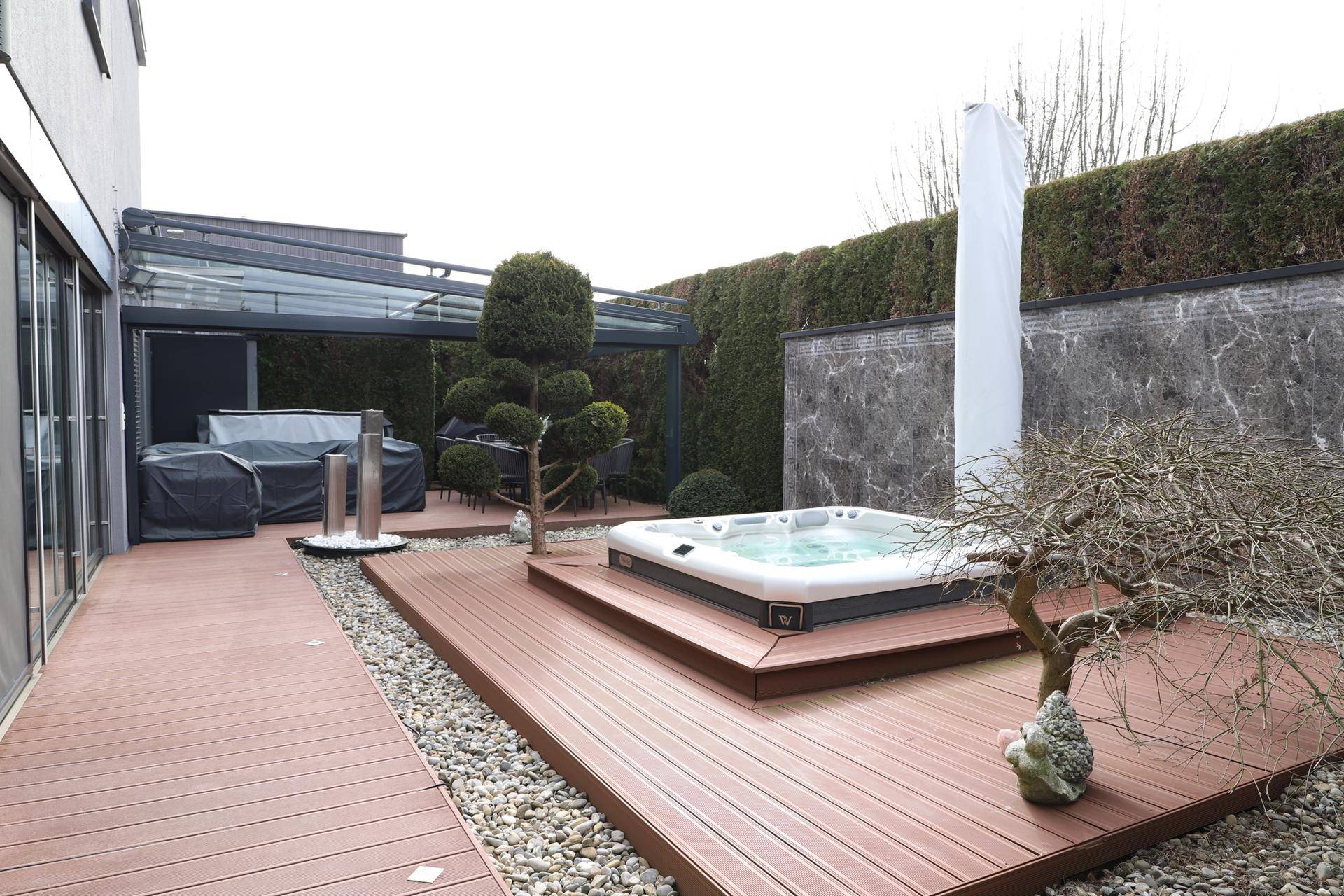 Großzügige Terrasse mit Holzdeck, Whirlpool und überdachtem Bereich für entspannte Stunden.