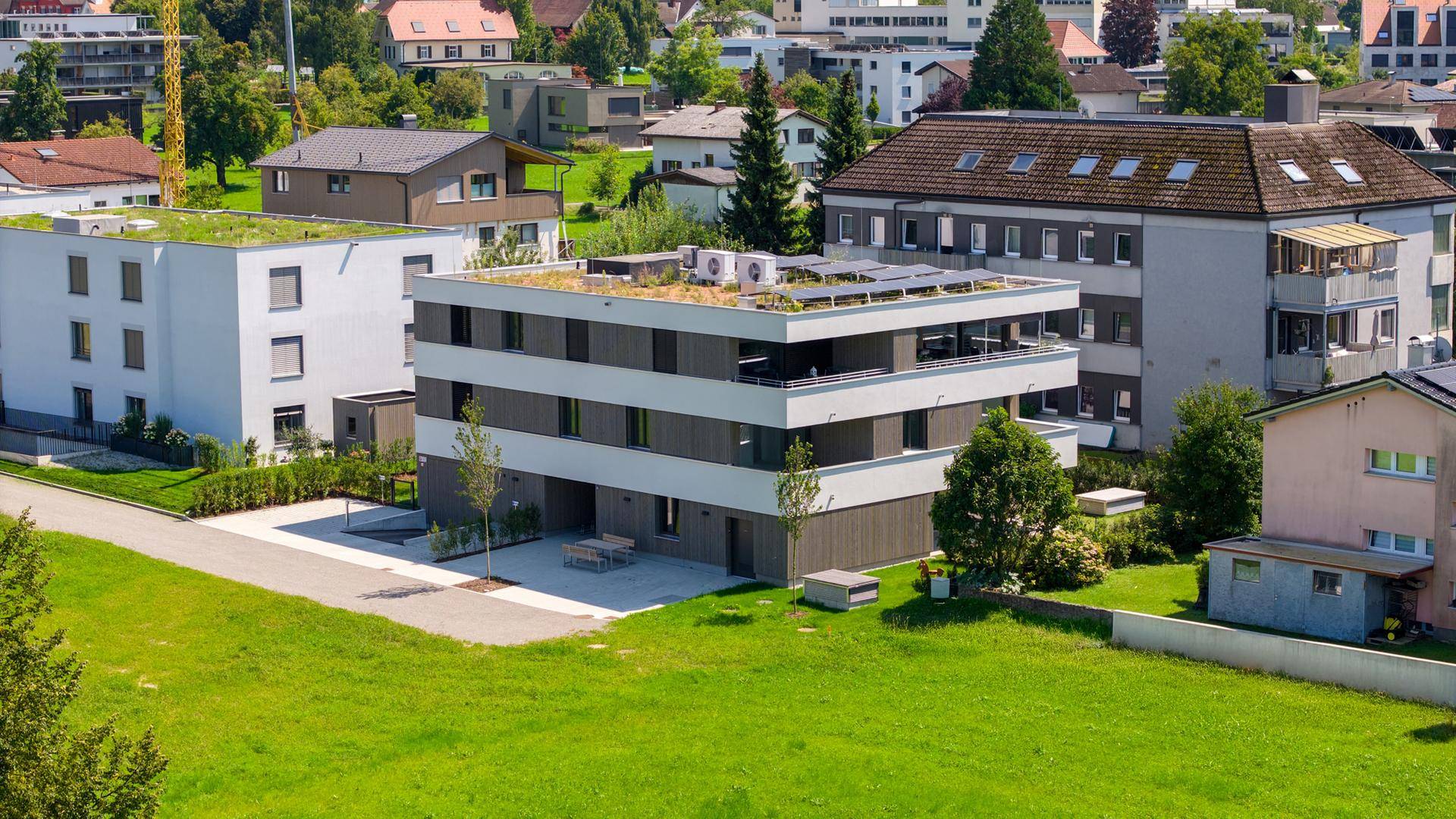 Luftaufnahme des modernen Wohngebäudes mit Gründach und Photovoltaikanlage in ländlicher Umgebung.