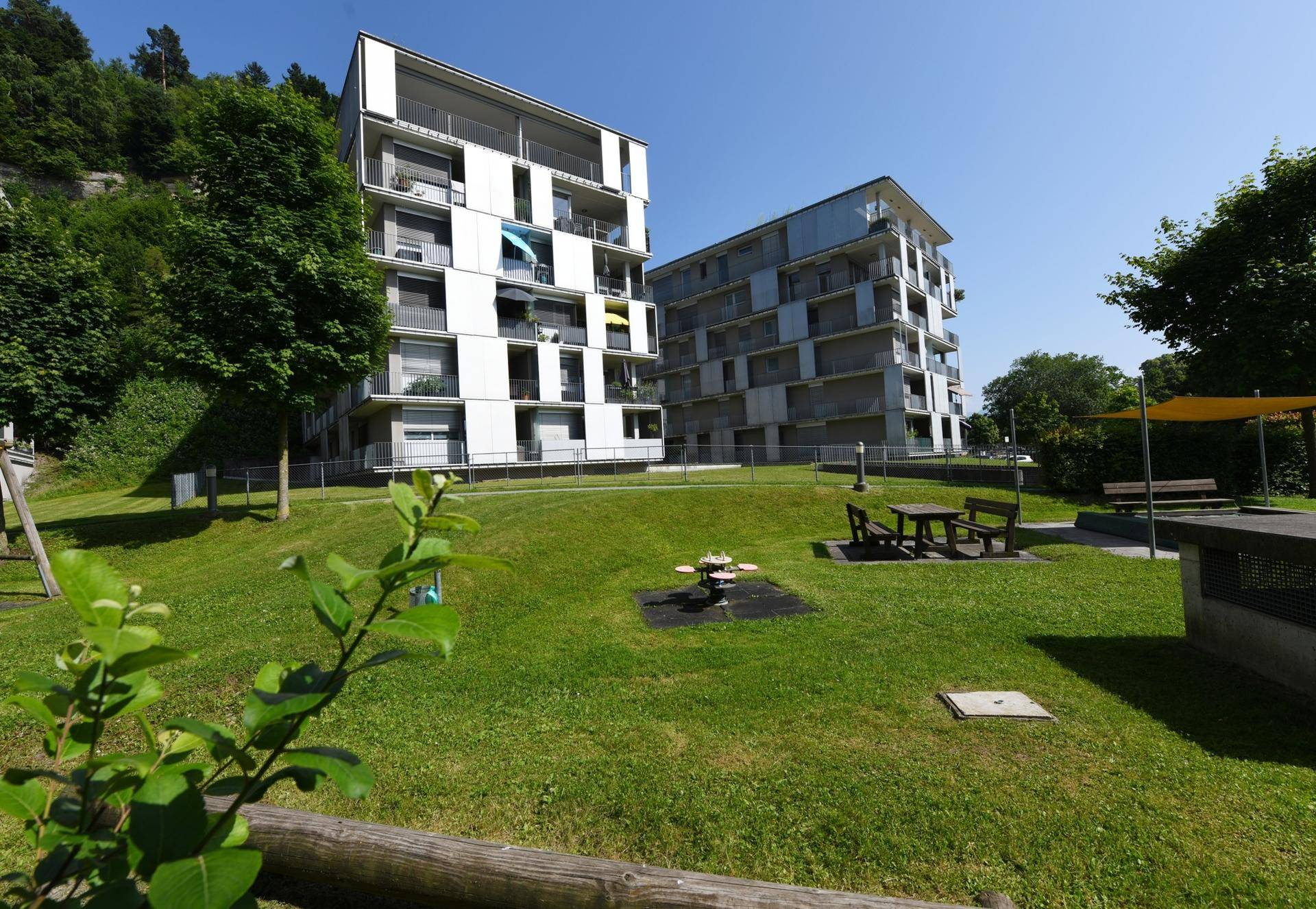 Moderne Wohngebäude mit gepflegter Grünfläche und kleinem Spielplatz im Freien.