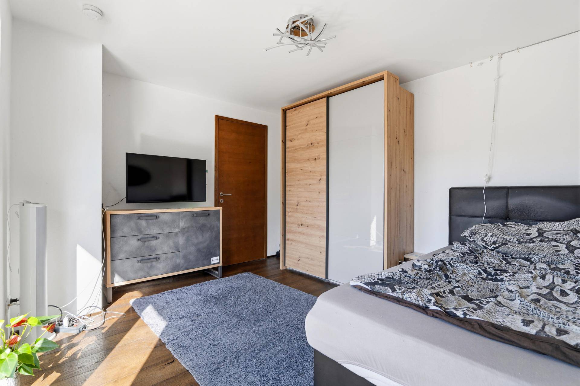 Schlafzimmer mit Holzboden, Kleiderschrank und modernem Dekor.