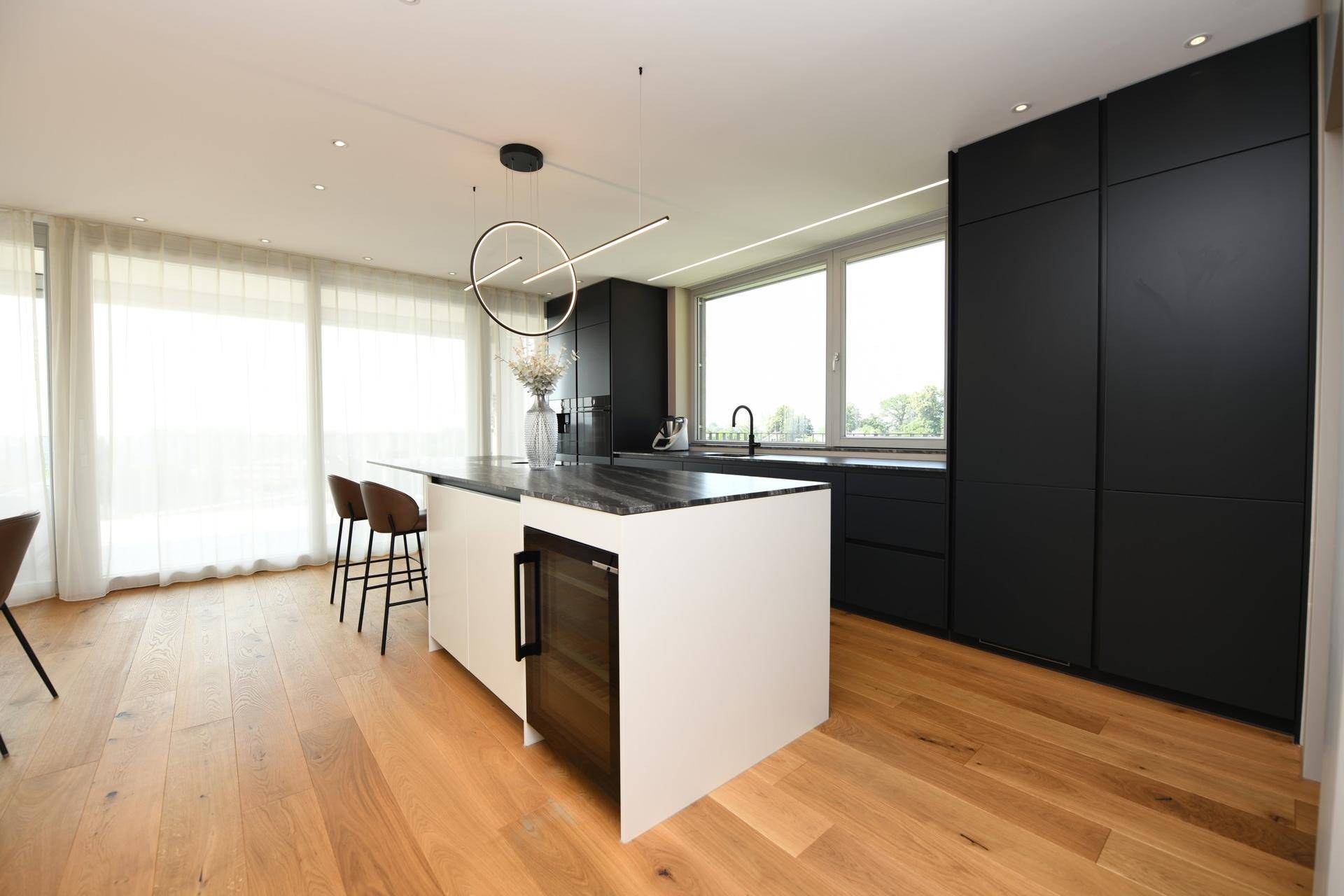 Moderne Küche mit schwarzem Design, Kücheninsel und integriertem Weinkühler.