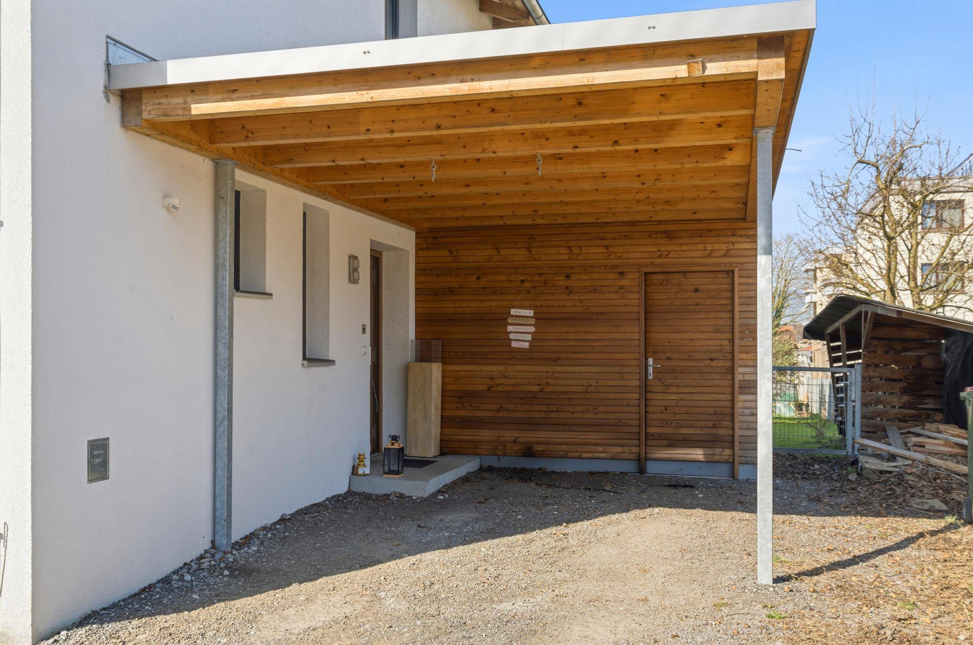 Überdachter Carport mit Holzelementen und Zugang zum Hauseingang.