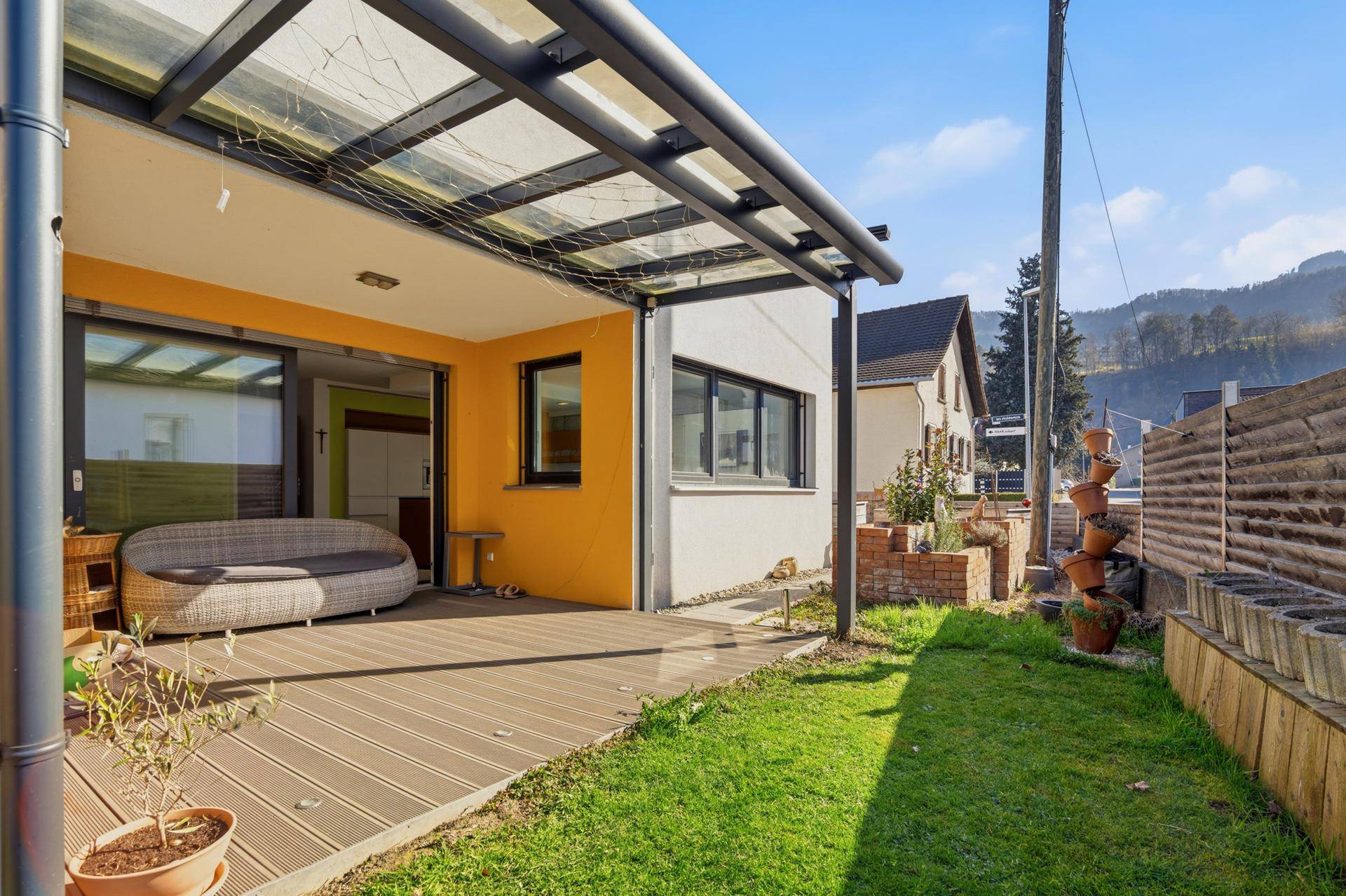 Sonnige Terrasse mit Gartenbereich und Blick auf die umliegende Natur.