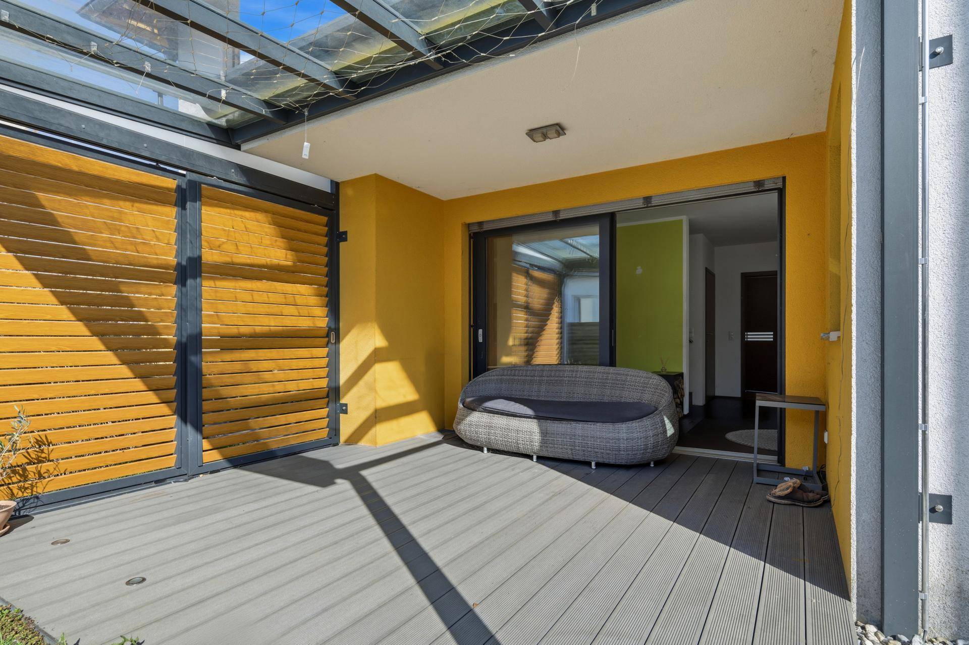 Überdachte Terrasse mit Lounge-Möbeln und Zugang zum Wohnbereich.