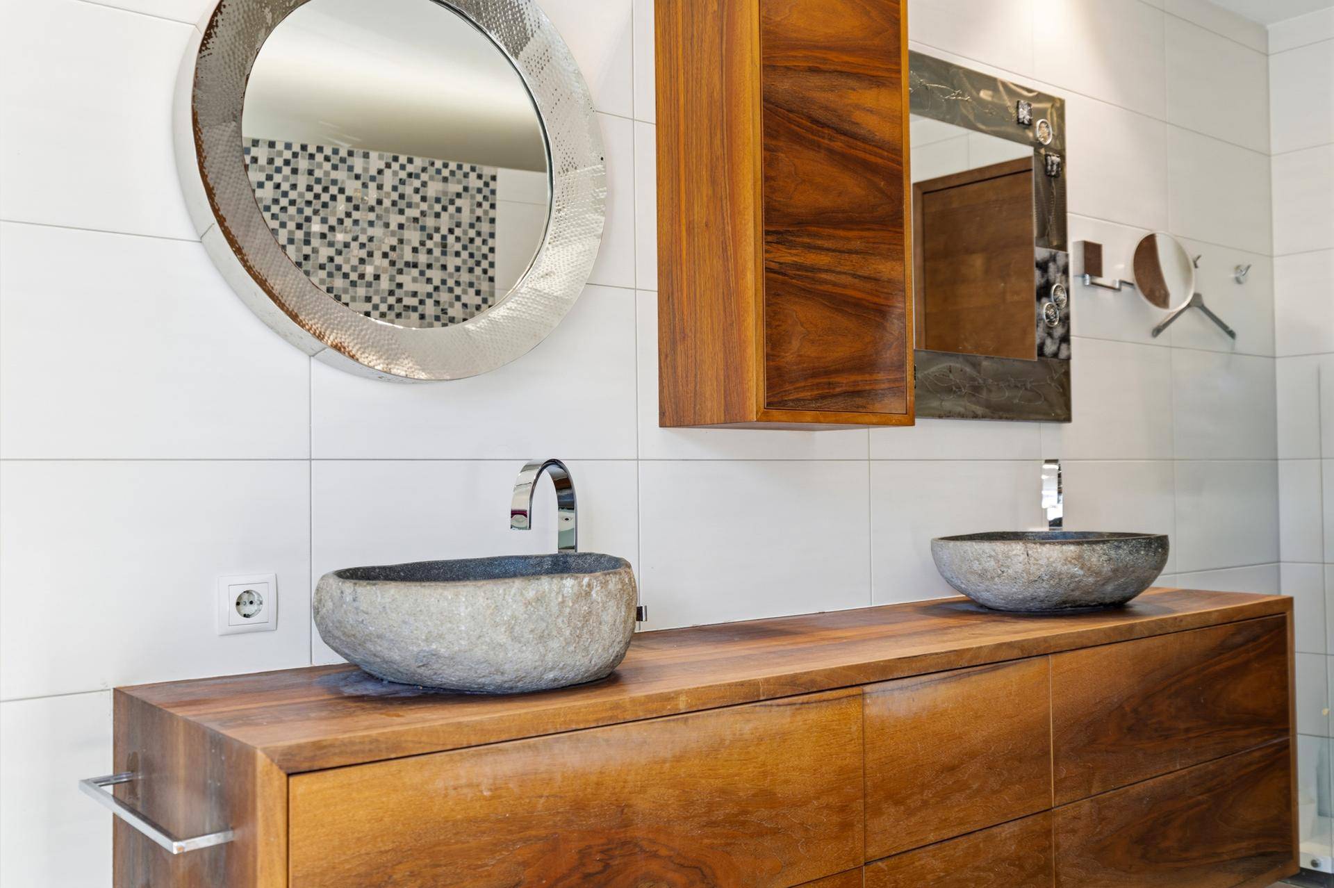 Detailansicht des Badezimmers mit zwei runden Steinwaschbecken und großem Spiegel.