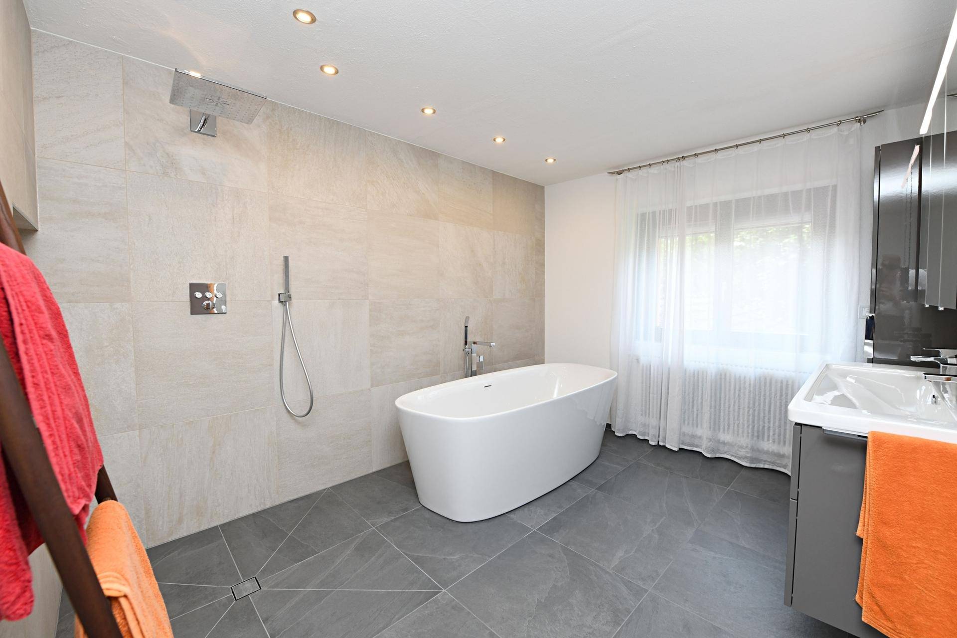 Modernes Badezimmer mit freistehender Badewanne, großer begehbarer Dusche und Fenster.