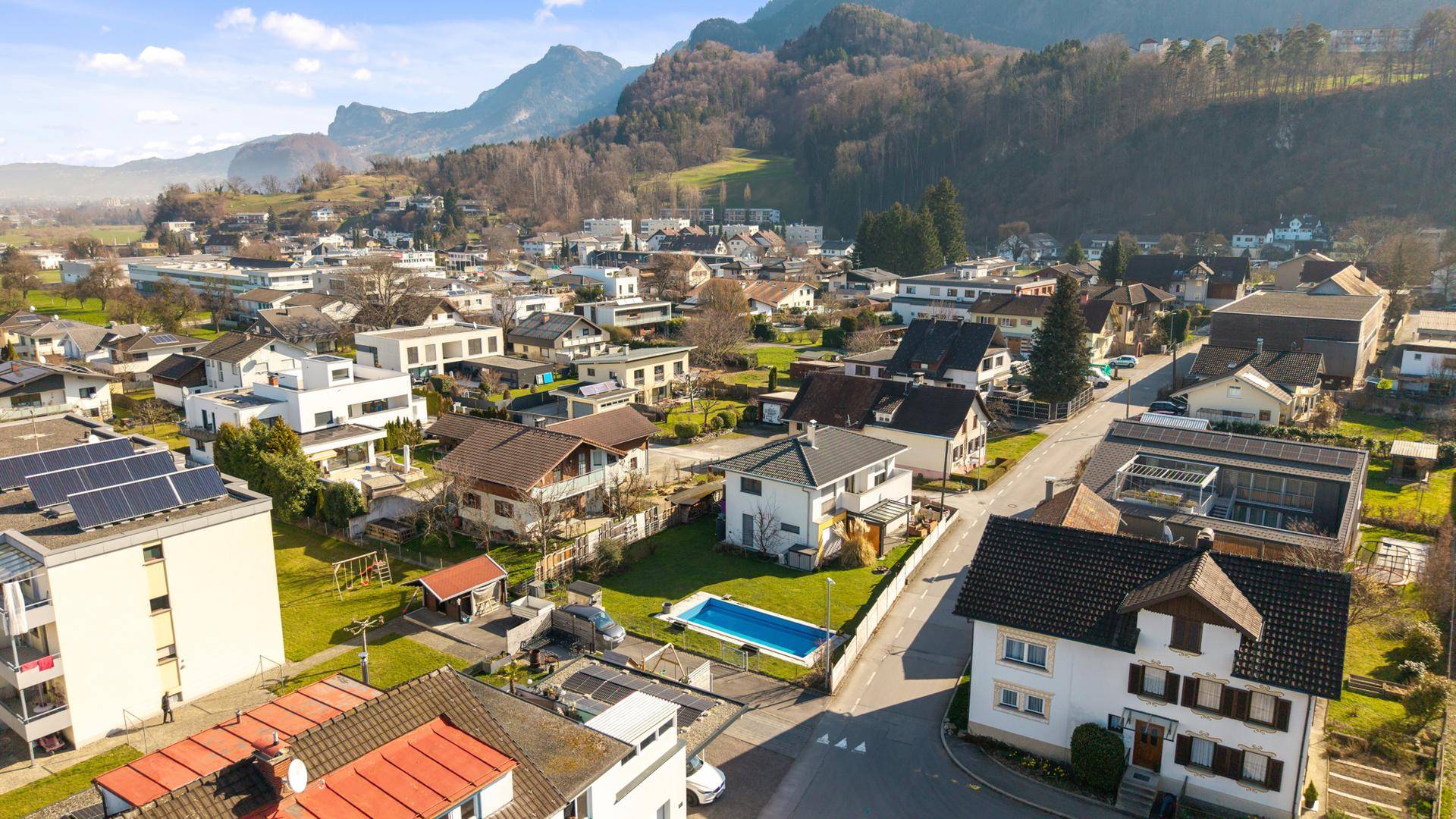 Panoramablick aus der Luft auf eine Siedlung mit Bergen im Hintergrund.