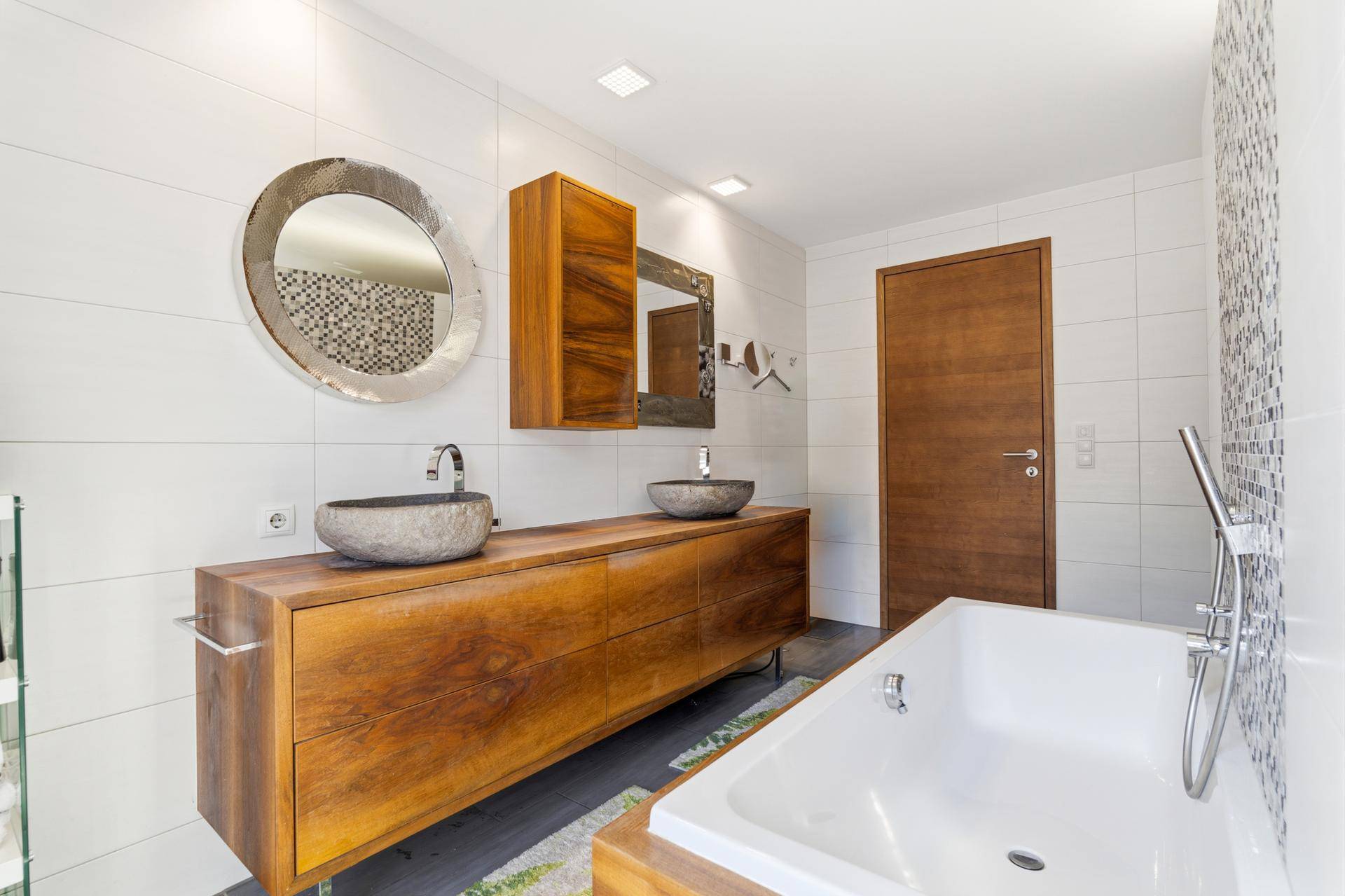 Elegantes Badezimmer mit zwei Steinwaschbecken auf Holzunterschrank und Badewanne.