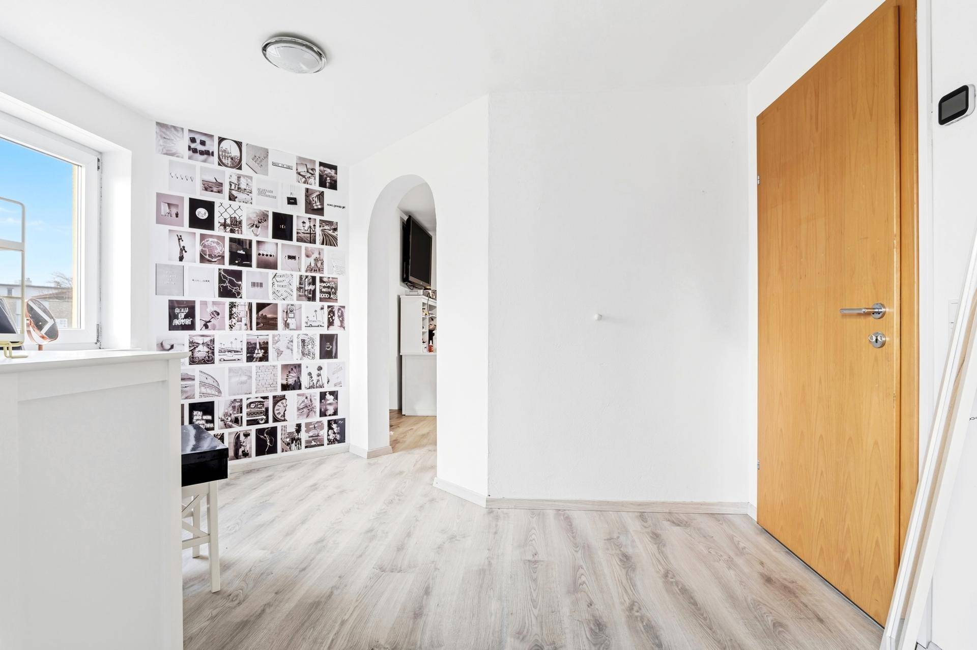 Heller Flur mit Laminatboden und dekorierter Wand, führt zu weiteren Räumen.