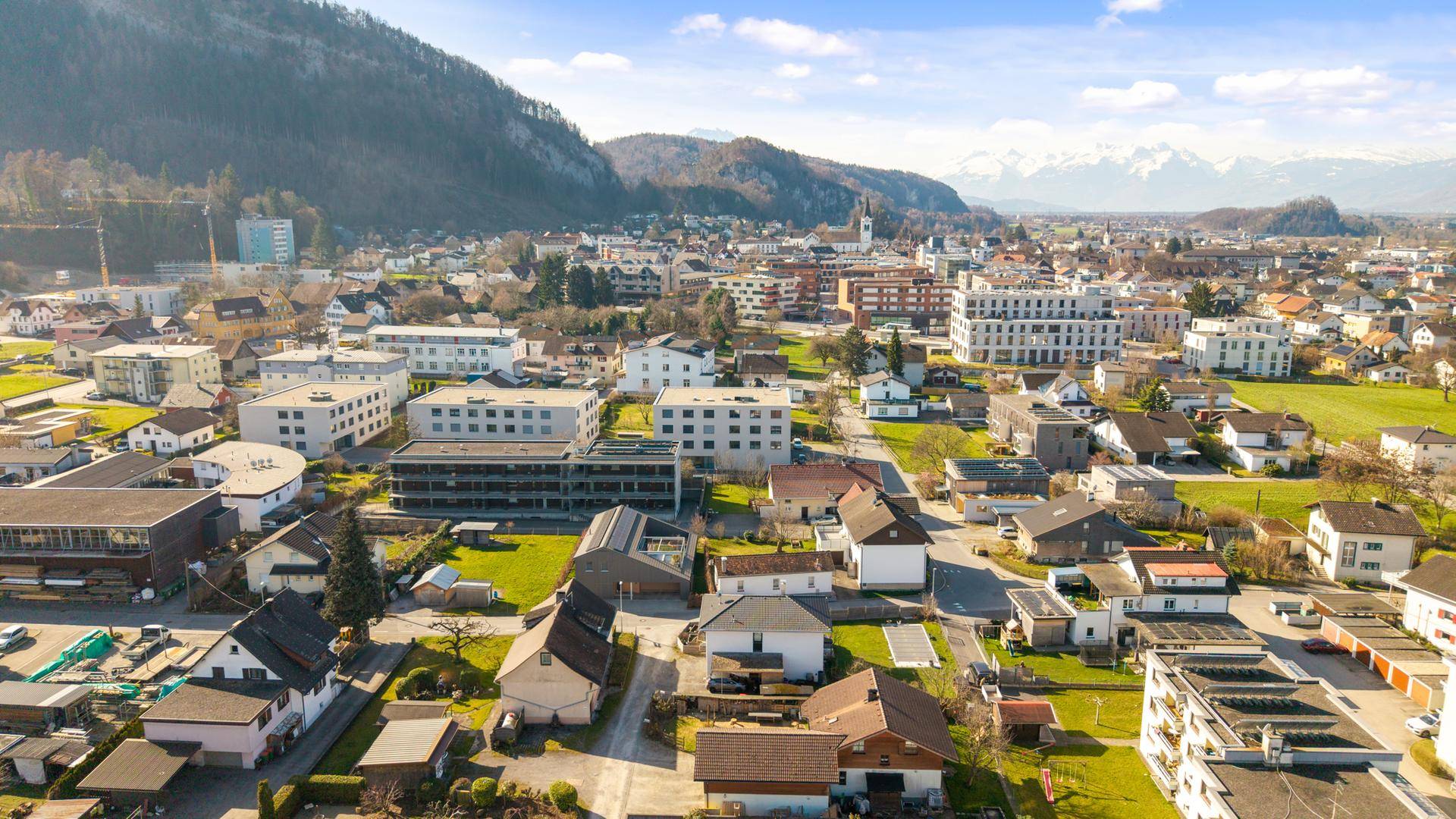 Luftaufnahme einer Wohnsiedlung mit Blick auf die umliegende Landschaft und Berge.