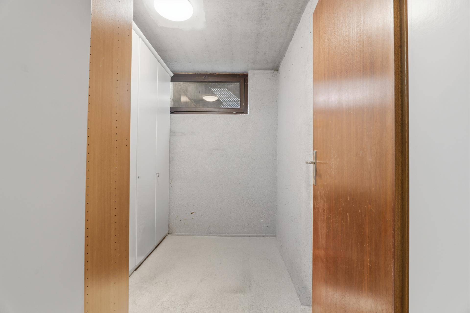 Einfacher Abstellraum im Keller mit Regalen und kleinem Fenster.