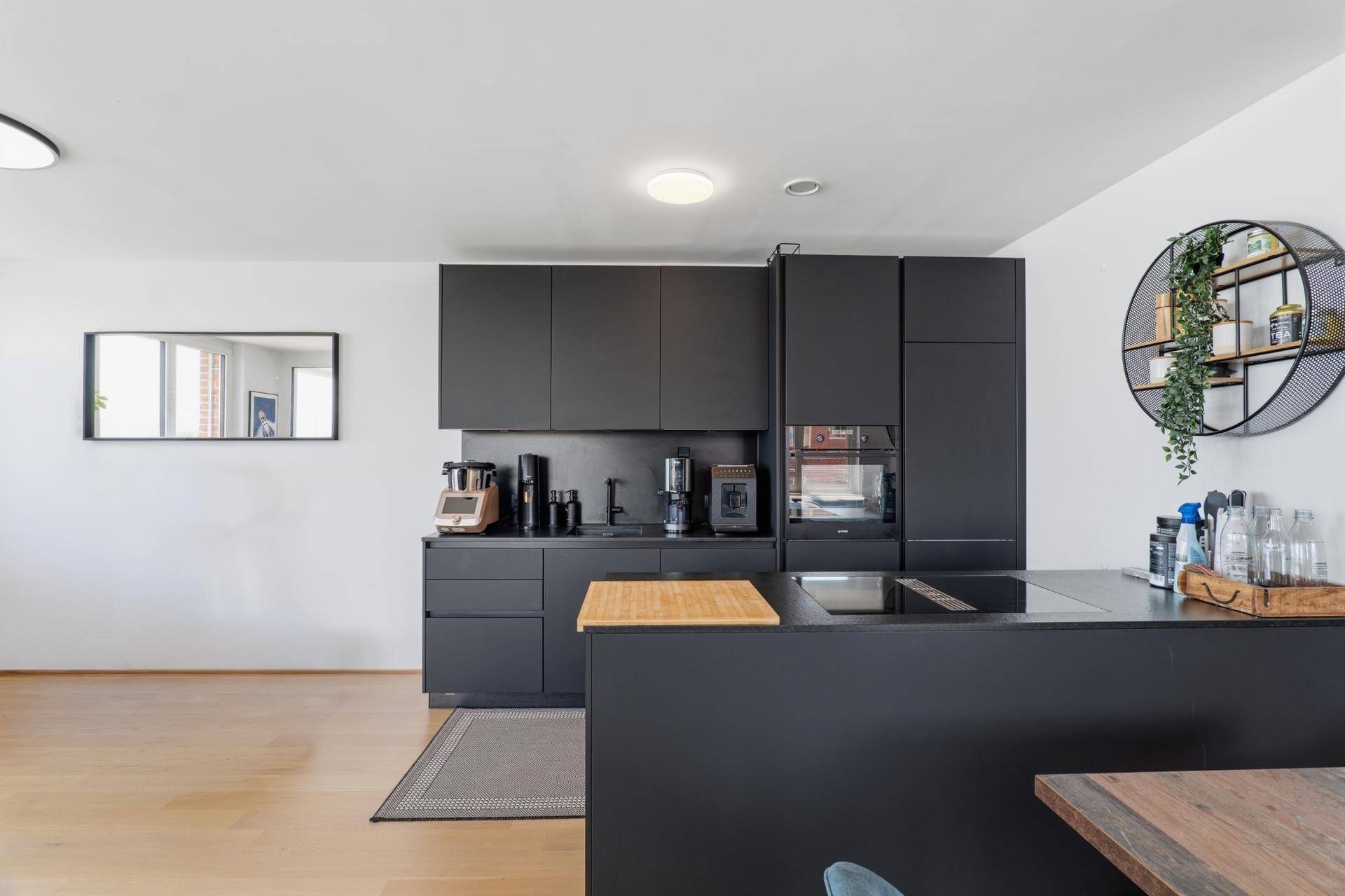 Elegante moderne Küche in Schwarz mit integrierten Geräten und einer praktischen Kücheninsel.