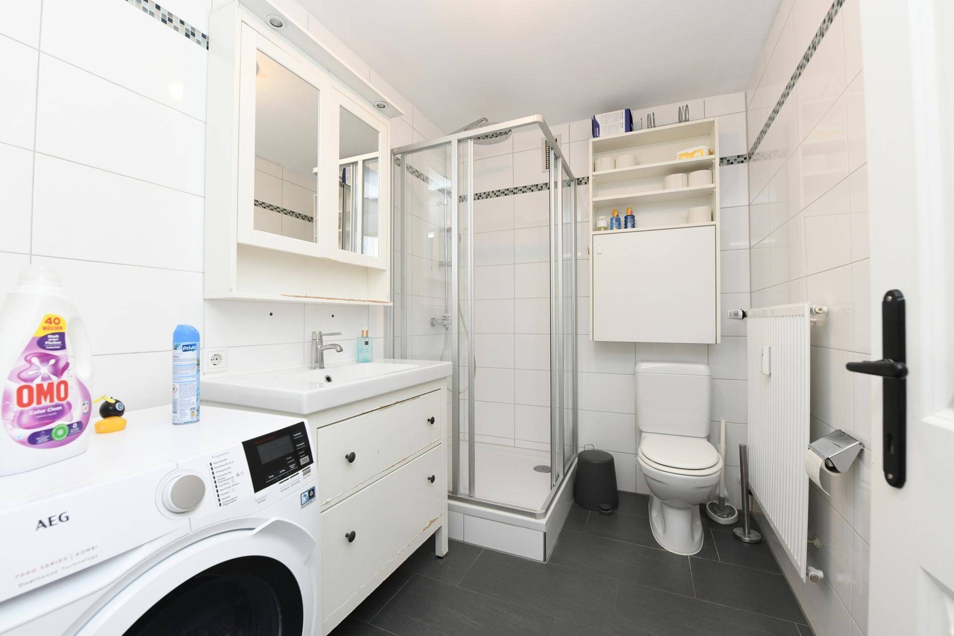Modernes Badezimmer mit Dusche, Waschbecken und integrierter Waschmaschine.