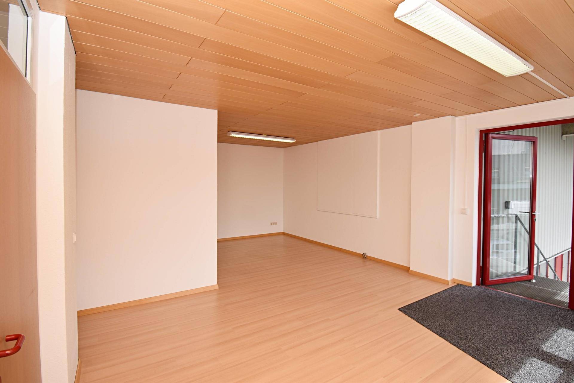 Heller, leerer Raum mit Laminatboden und Holzdecke, bereit zur individuellen Gestaltung.