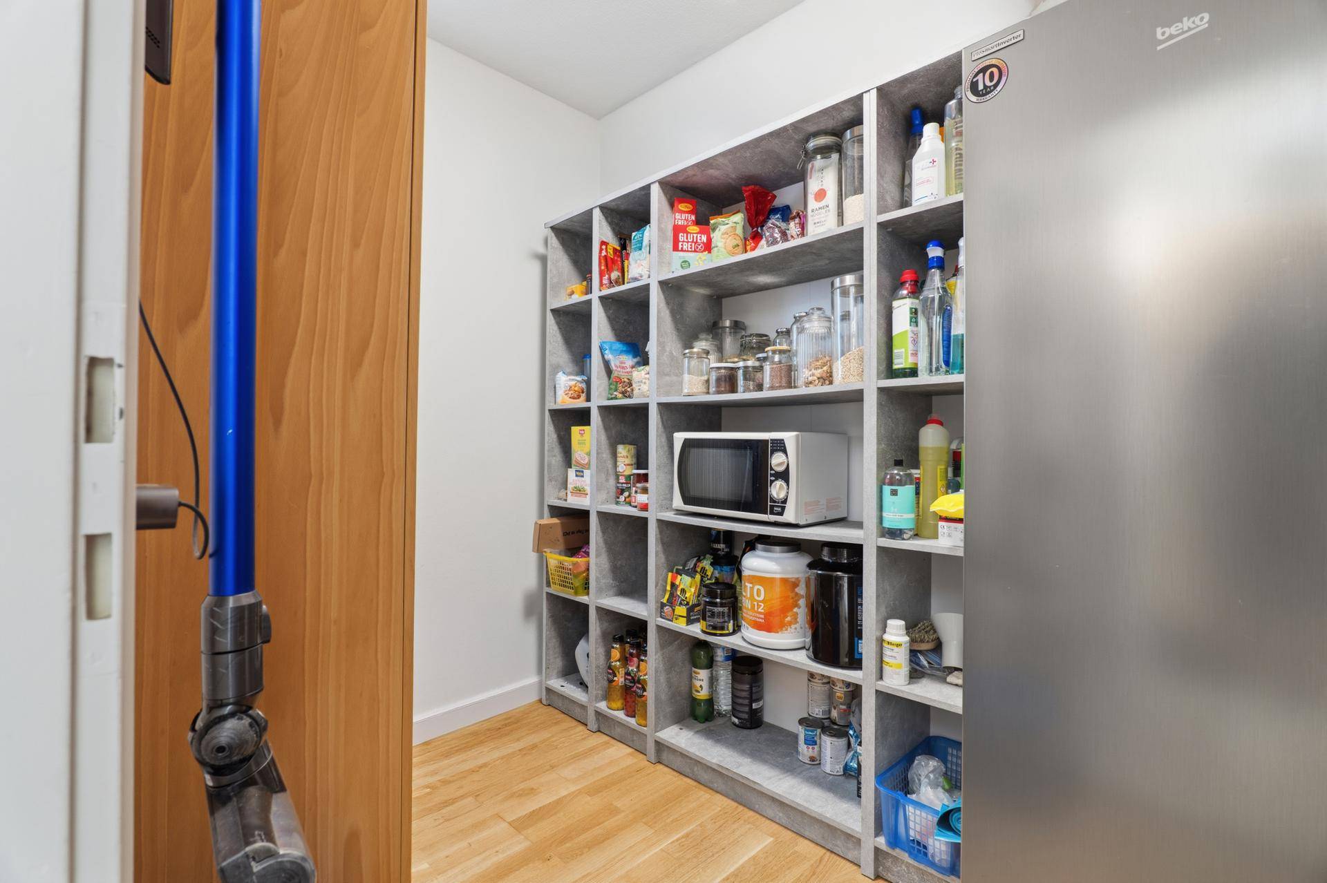 Praktische Speisekammer mit Regalen für Vorräte und einem Kühlschrank.