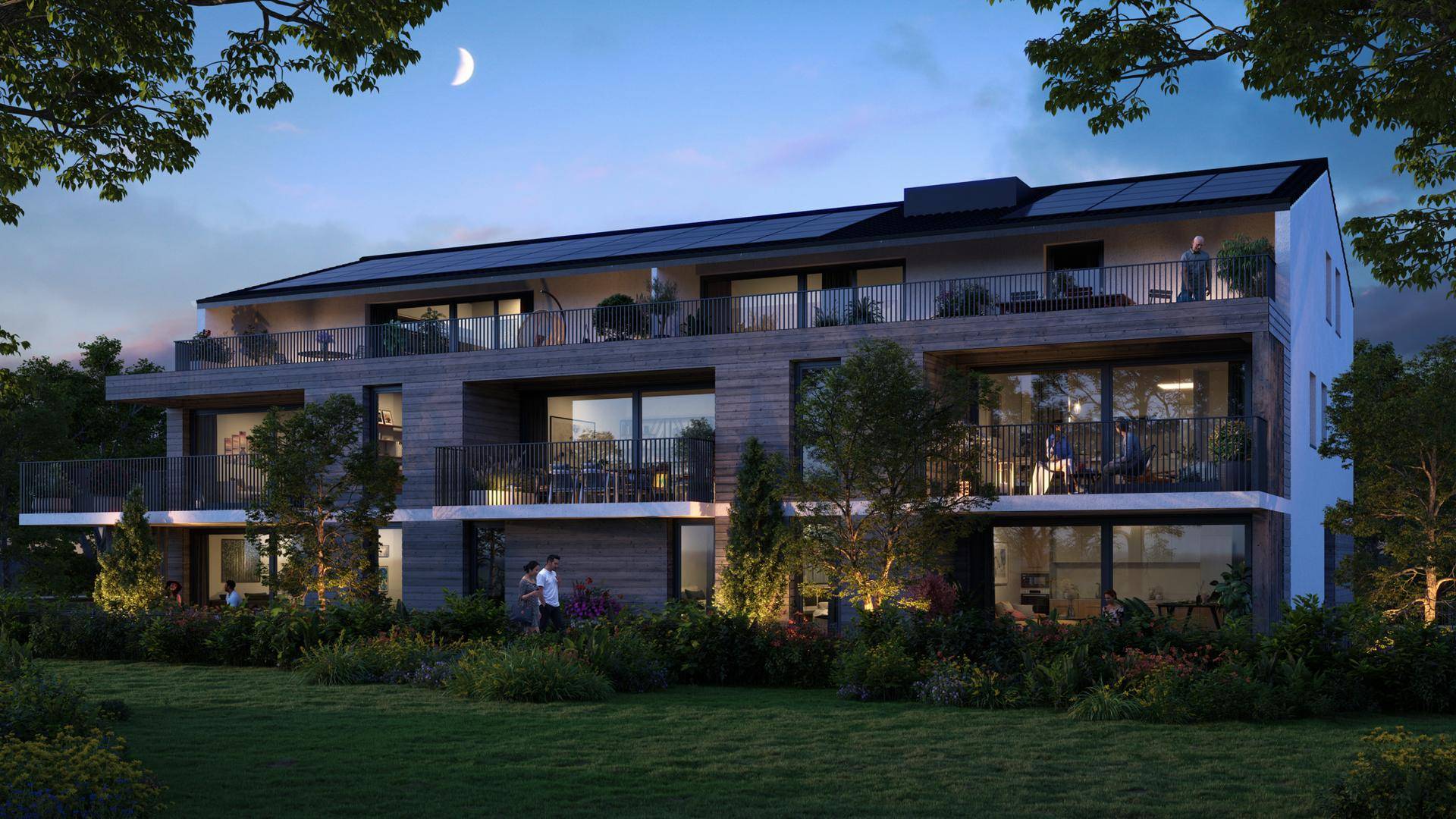 Abendliche Ansicht des modernen Wohnhauses mit beleuchteten Balkonen, Terrassen und Photovoltaikanlage.
