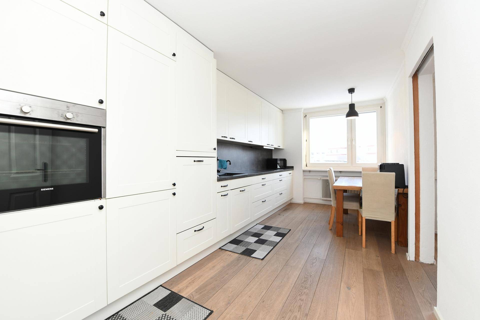 Moderne Einbauküche in Weiß mit Essbereich und integriertem Siemens Backofen.