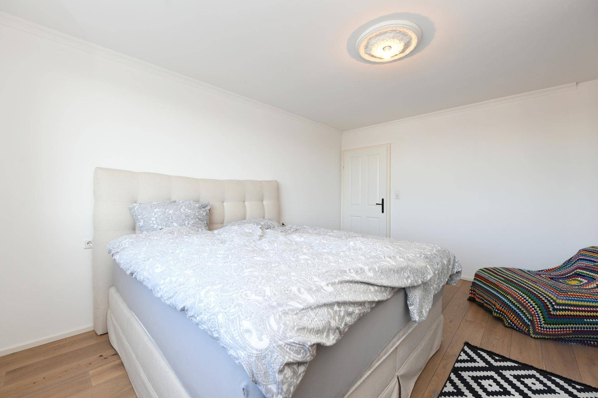 Gemütliches Schlafzimmer mit Doppelbett und Holzboden, hell und einladend.