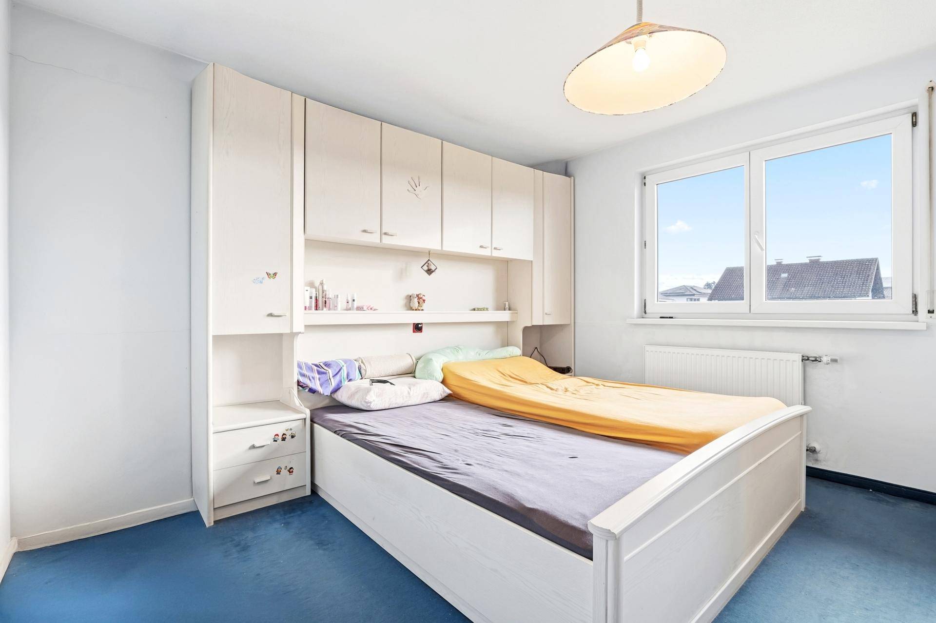 Schlafzimmer mit Einbauschränken, blauem Teppichboden und Fenster mit Ausblick.